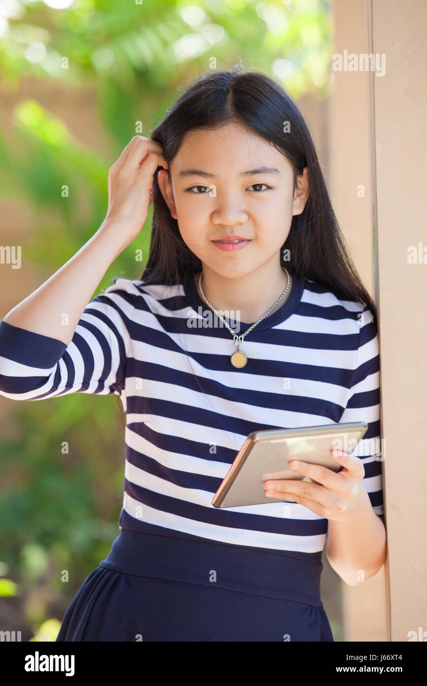 Ritratto di asian teen età ,ragazza con computer tablet in mano in piedi con felicità e relax emozione uso esterno per il moderno stile di vita digitale Foto Stock