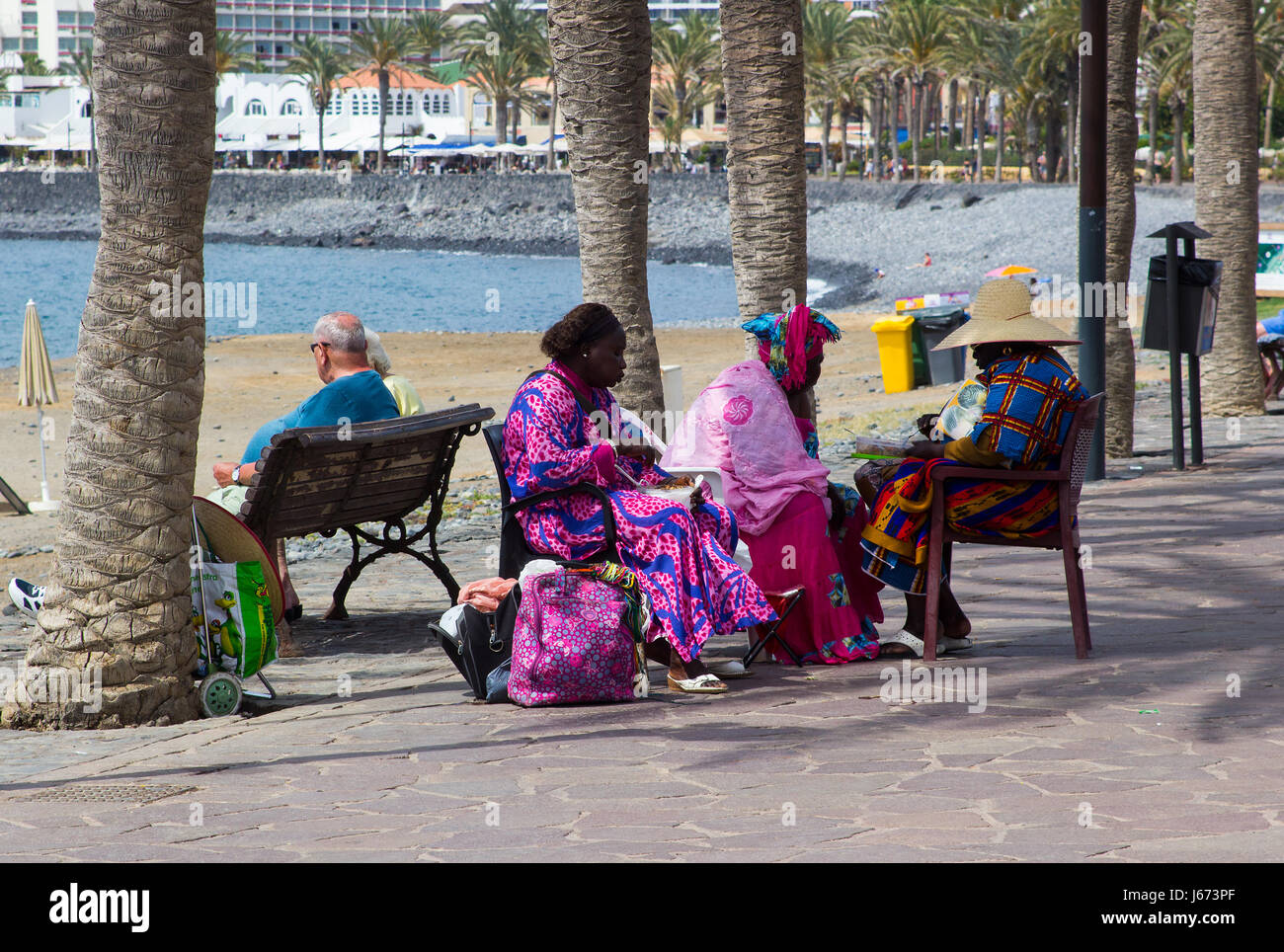 Un gruppo di West African sorelle godersi un meritato spuntino come prendere un periodo di riposo dal loro capelli business da intreccio per turisti sul lungomare di Playa Foto Stock