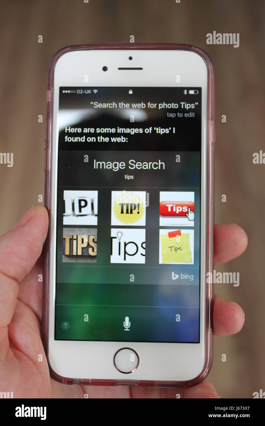 Iphone 6s essendo tenuto vicino durante una ricerca vocale con Siri per consigli per le foto Foto Stock