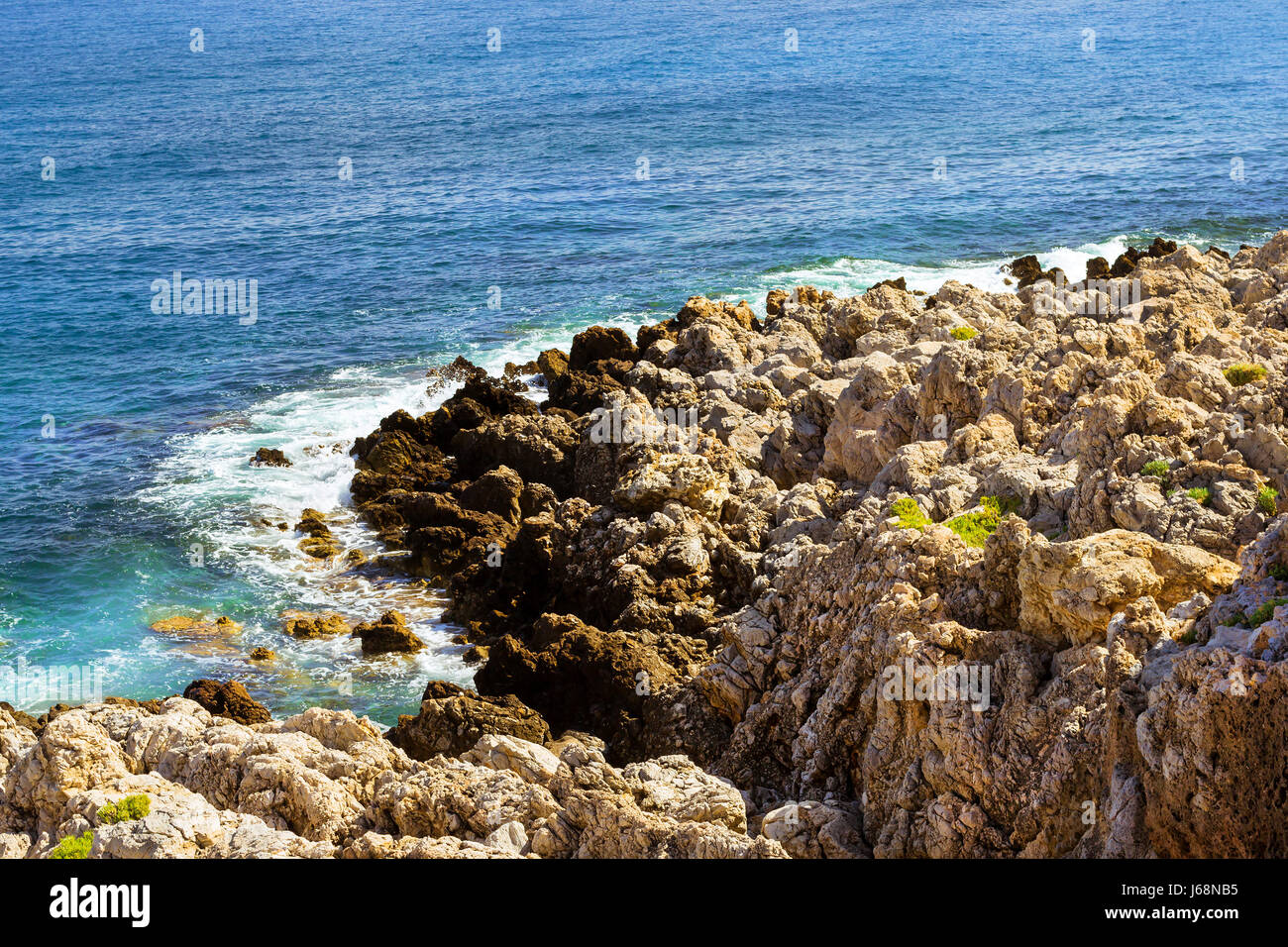 Le onde rompono sulla spiaggia rocciosa. Infuria un mare di un potere elementare in una tempesta. Giorno chiaro in mare costa. Tourist beach resort nel resort Rethymno. Costa di Kolpos Foto Stock