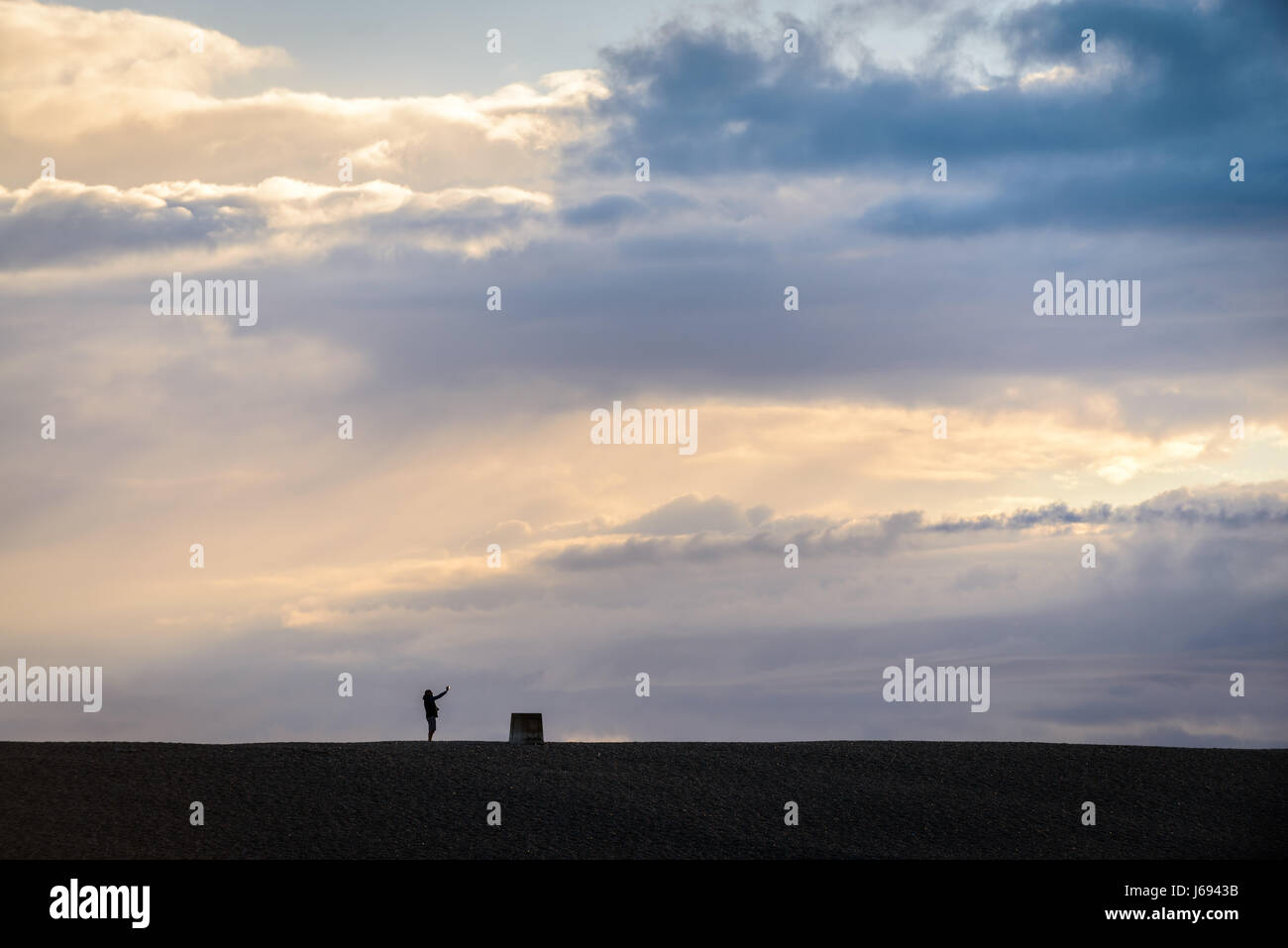 Chesil Beach, Portland, Dorset, Regno Unito. 19 Maggio, 2017. Un uomo prende un selfie su Chesil Beach con un burrascoso cloudu sullo sfondo. Credito: Dan Tucker/Alamy Live News Foto Stock