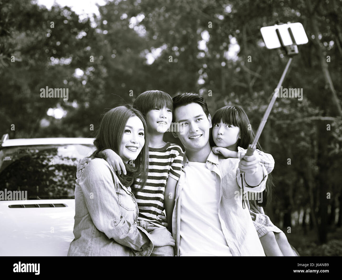 Famiglia asiatica con due bambini prendendo un selfie durante un viaggio e in bianco e nero. Foto Stock