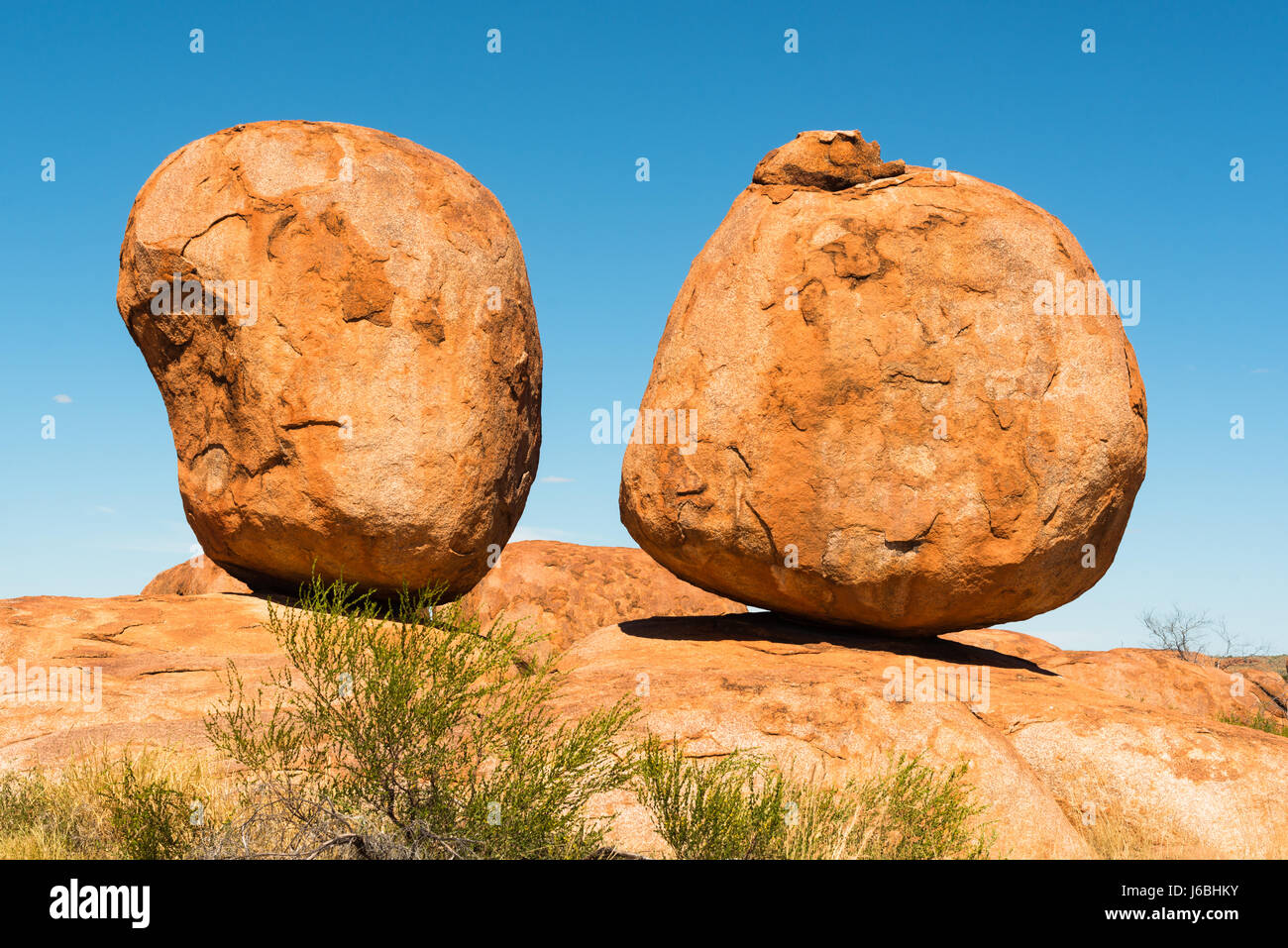 Devils Marmi - due quasi perfettamente sagomato circolare di massi di granito rosso sono bilanciati su roccia, Australia, Territorio del Nord. Foto Stock