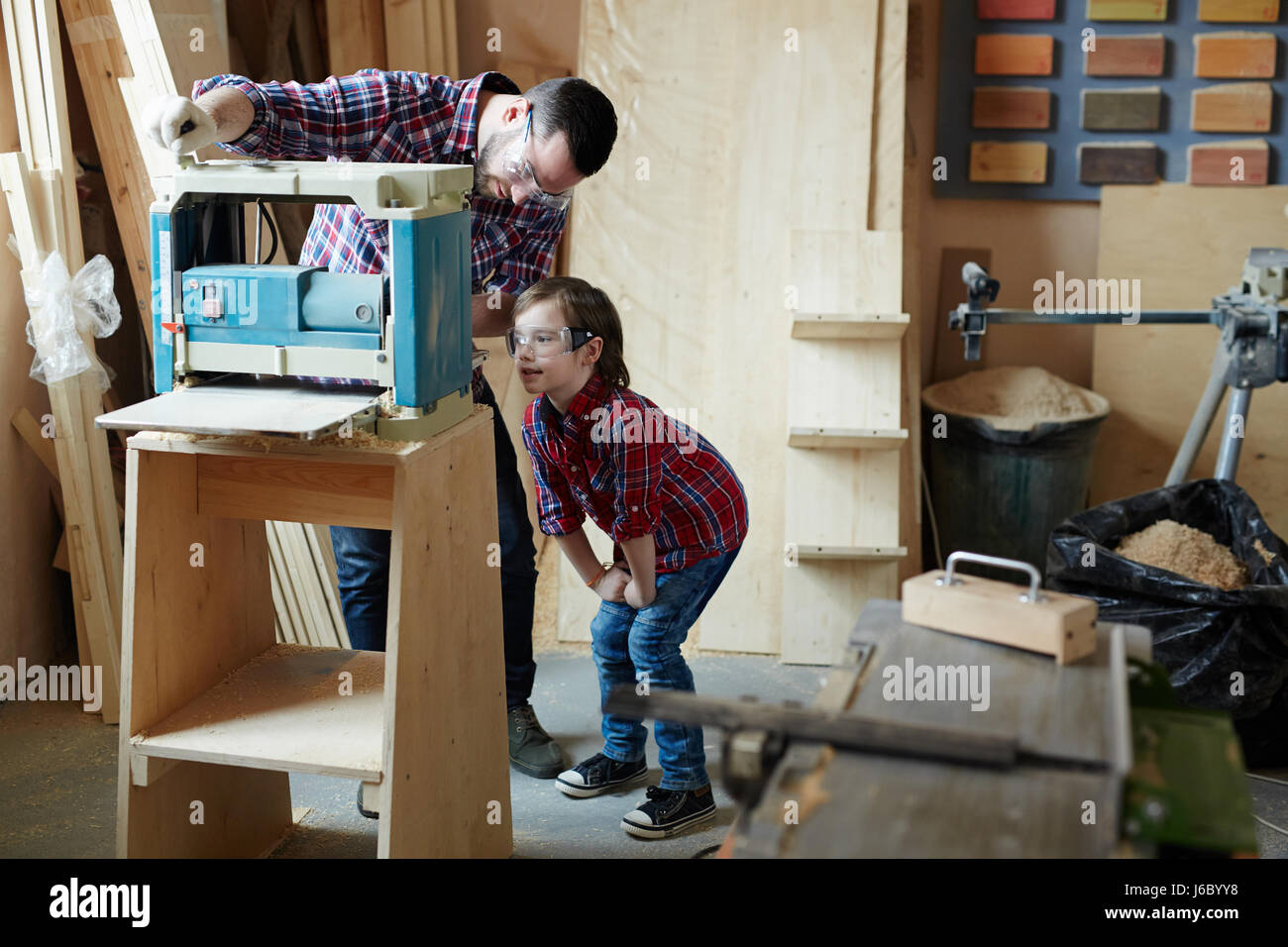 Giovane uomo che mostra il suo Figlio come lavorare sulla macchina di piallatura Foto Stock