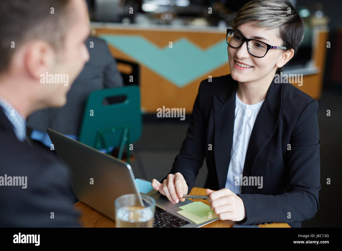 Ritratto di giovane imprenditrice creativa di parlare all'uomo a tavola, mentre a discutere di questioni di lavoro e sorridente Foto Stock