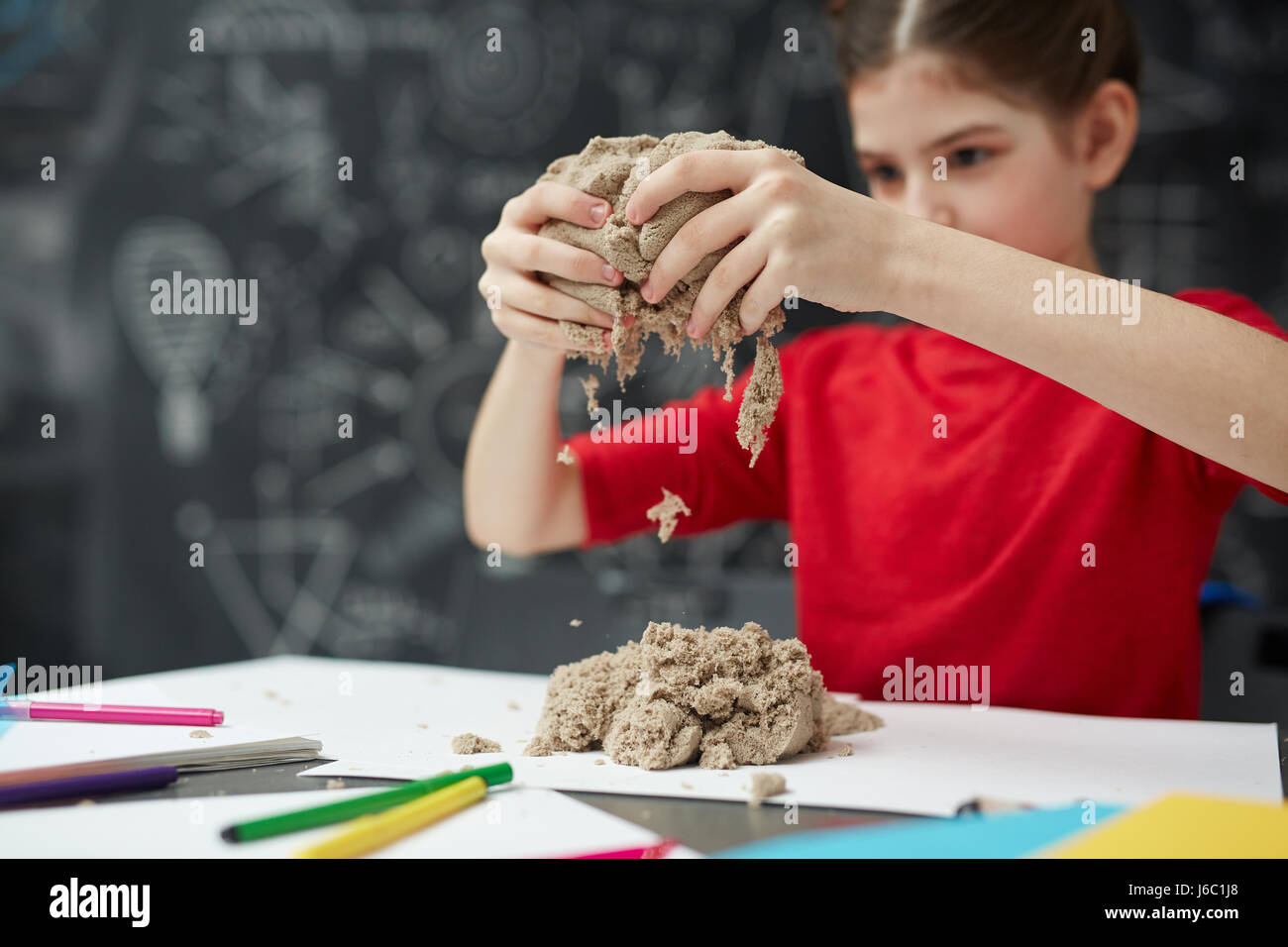 Ritratto di bambina gioca con la sabbia cinetica durante l arte in classe child development center, concentrarsi sulla sabbia in mani Foto Stock