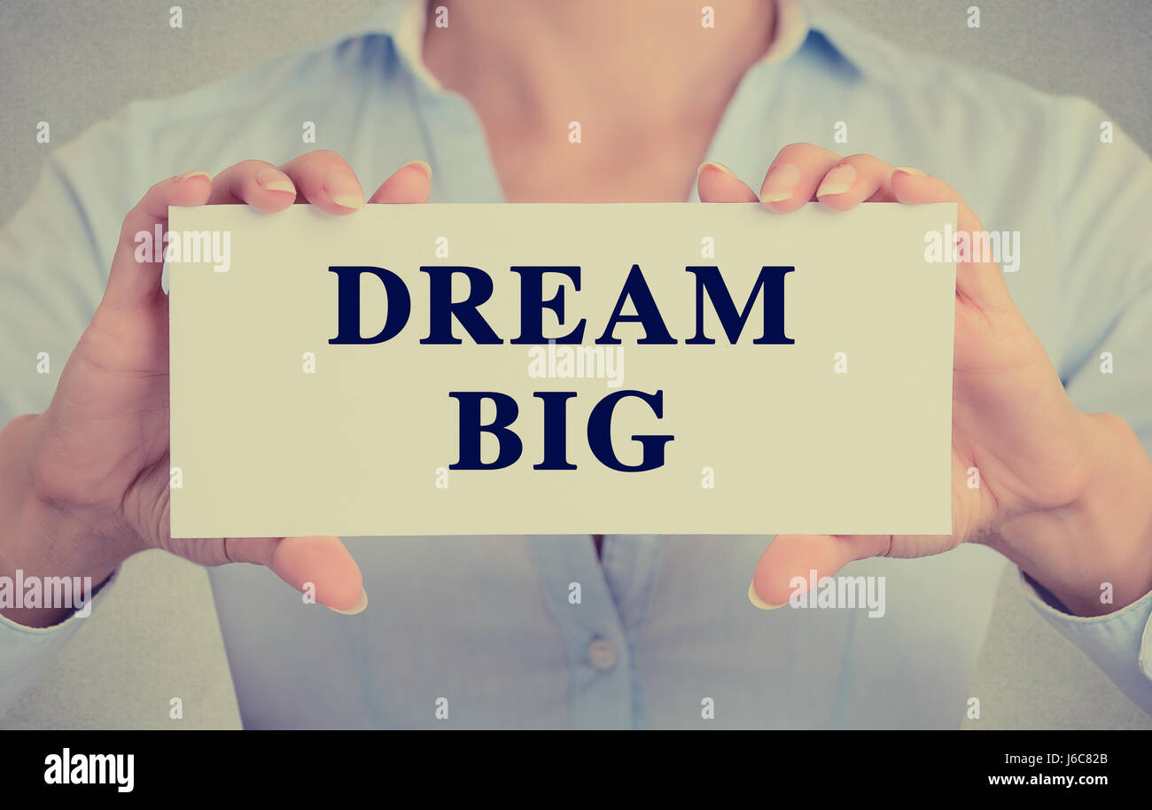 Retrò stile instagram immagine imprenditrice mani carta bianca con grande sogno una frase di testo isolato di segno sul muro grigio office background. Foto Stock
