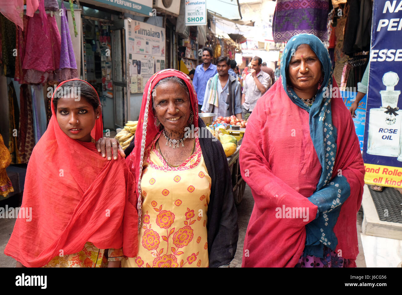 Tre donne indiane con velo colorato e sari e un naso gioielli in posa sulla strada di Pushkar, Rajasthan, India Foto Stock