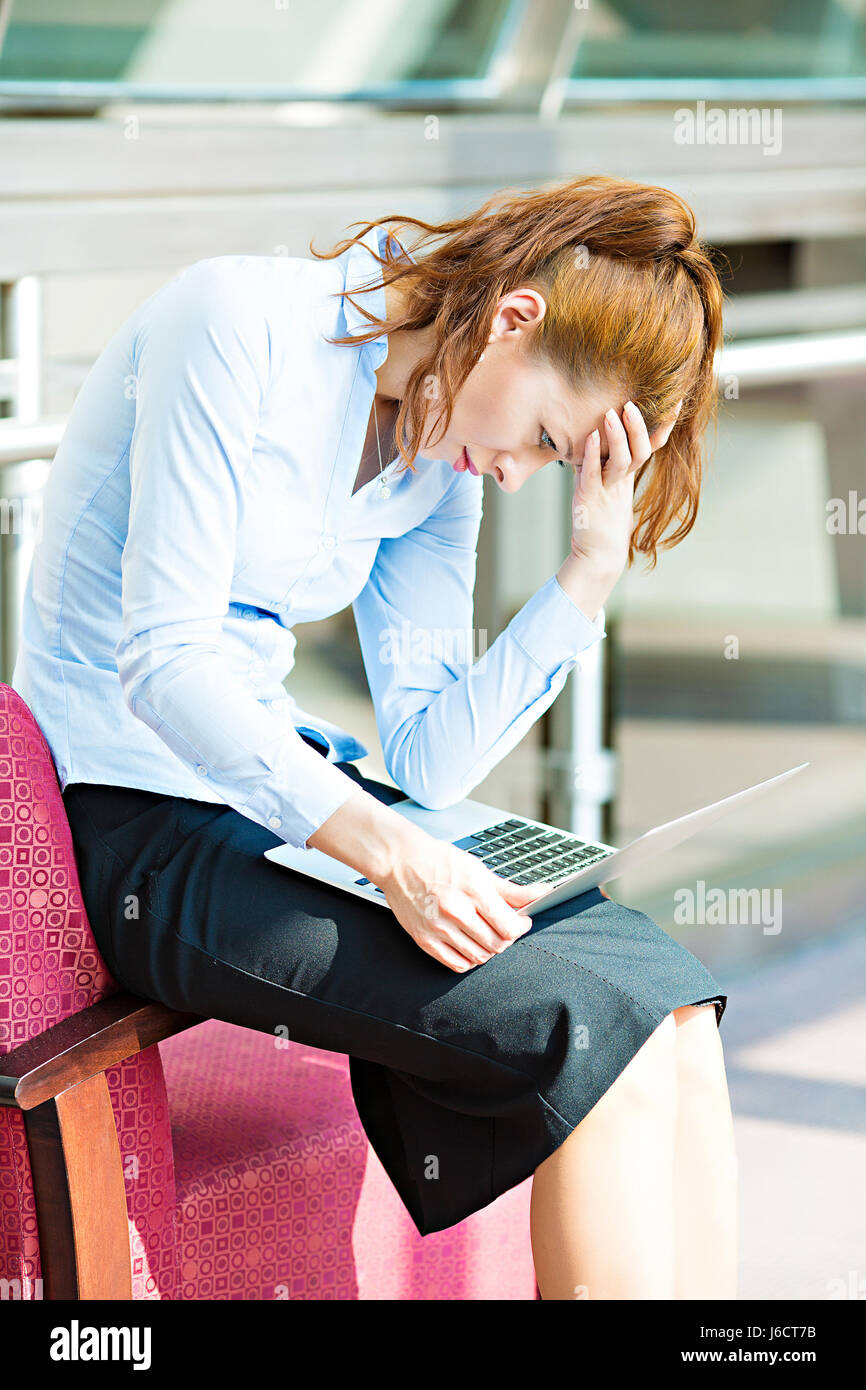 Closeup ritratto triste ha sottolineato, stanchi, sopraffatto business donna seduta sulla poltrona guardando lo schermo del suo computer portatile isolato corpor sfondo Foto Stock