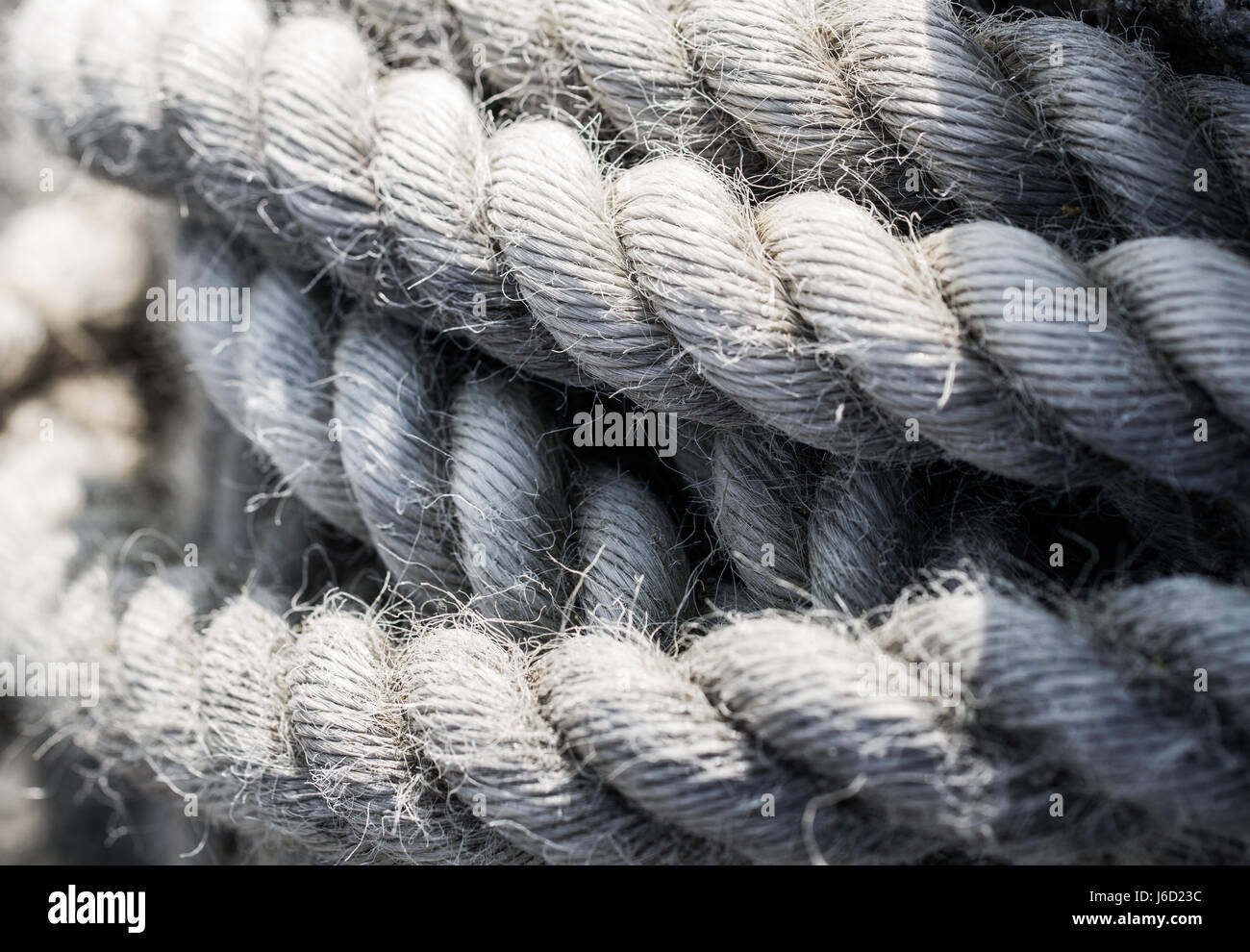 Un vicino, immagine di sfondo delle bobine di spessa e pesante che la corda è usurato, weathered e consumati e utilizzati per la spedizione e temi nautico. Foto Stock