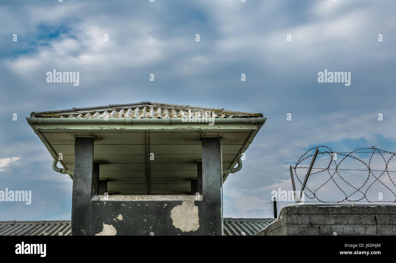 La sicurezza della torre di vedetta e filo spinato e rabboccato parete in corrispondenza di Robben Island Museum, il carcere di massima sicurezza, Cape Town, Sud Africa Foto Stock