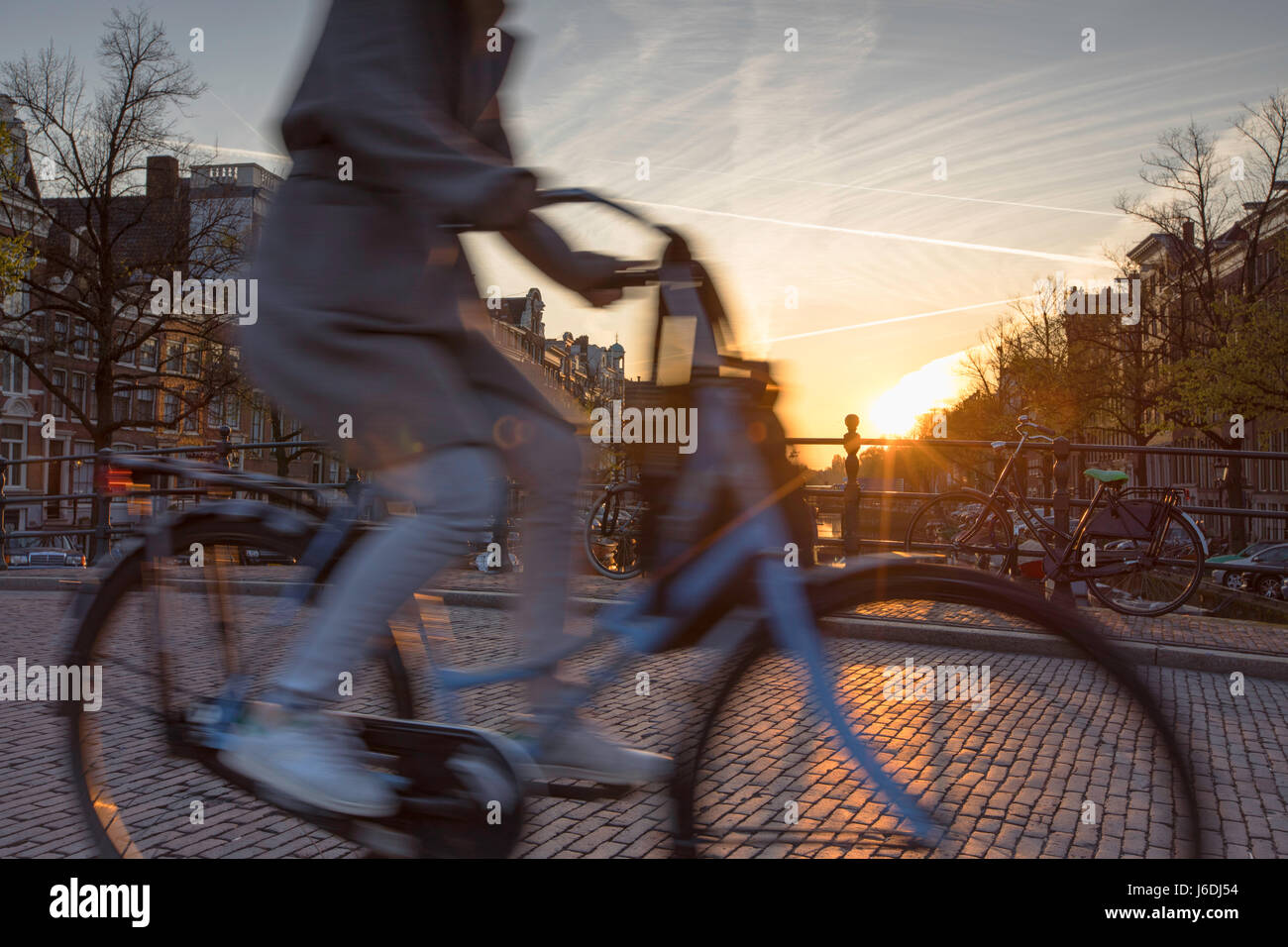 Ciclista attraversando ponte sul canale Keizersgracht all'alba, Amsterdam, Paesi Bassi Foto Stock