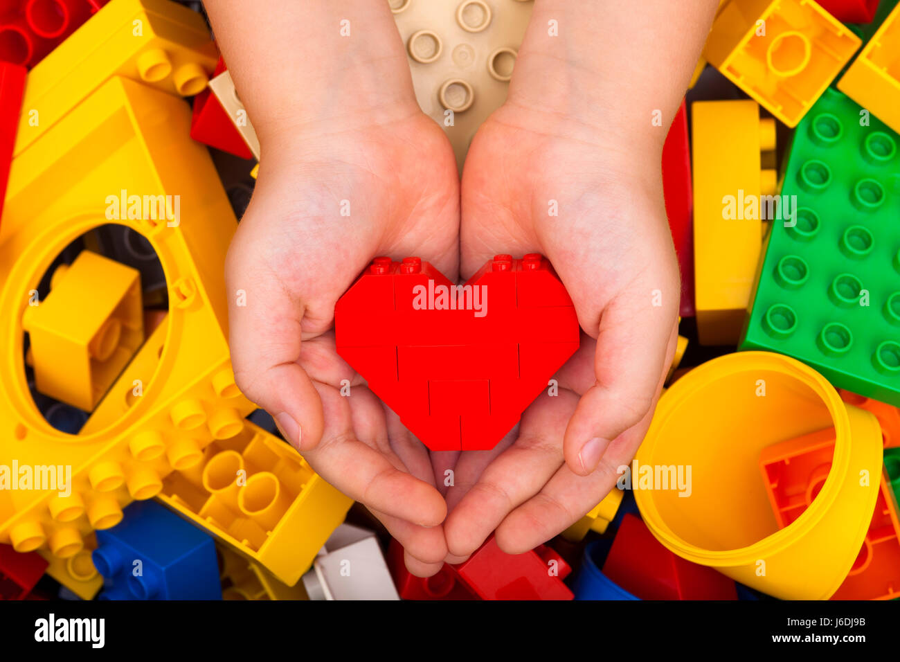 Tambov, Federazione Russa - Settembre 07, 2015 Lego cuore rosso nel bambino le palme con Lego Duplo blocchi dello sfondo. Studio shot. Foto Stock