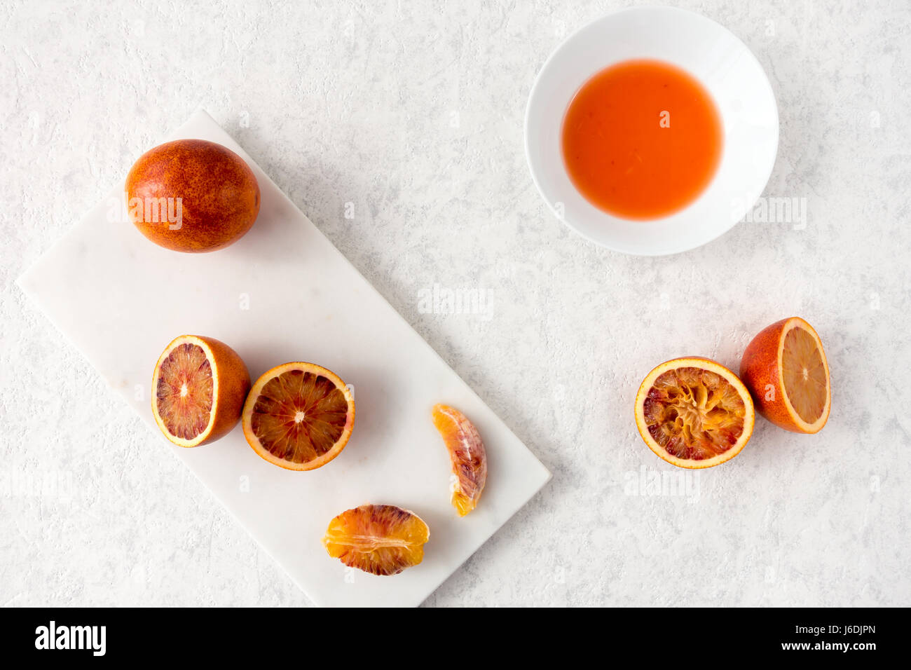 Tutto, dimezzata e spremuta di arance di sangue e succo di frutta fresco su marmo bianco tagliere e white texture di sfondo in marmo con copia spazio. Foto Stock