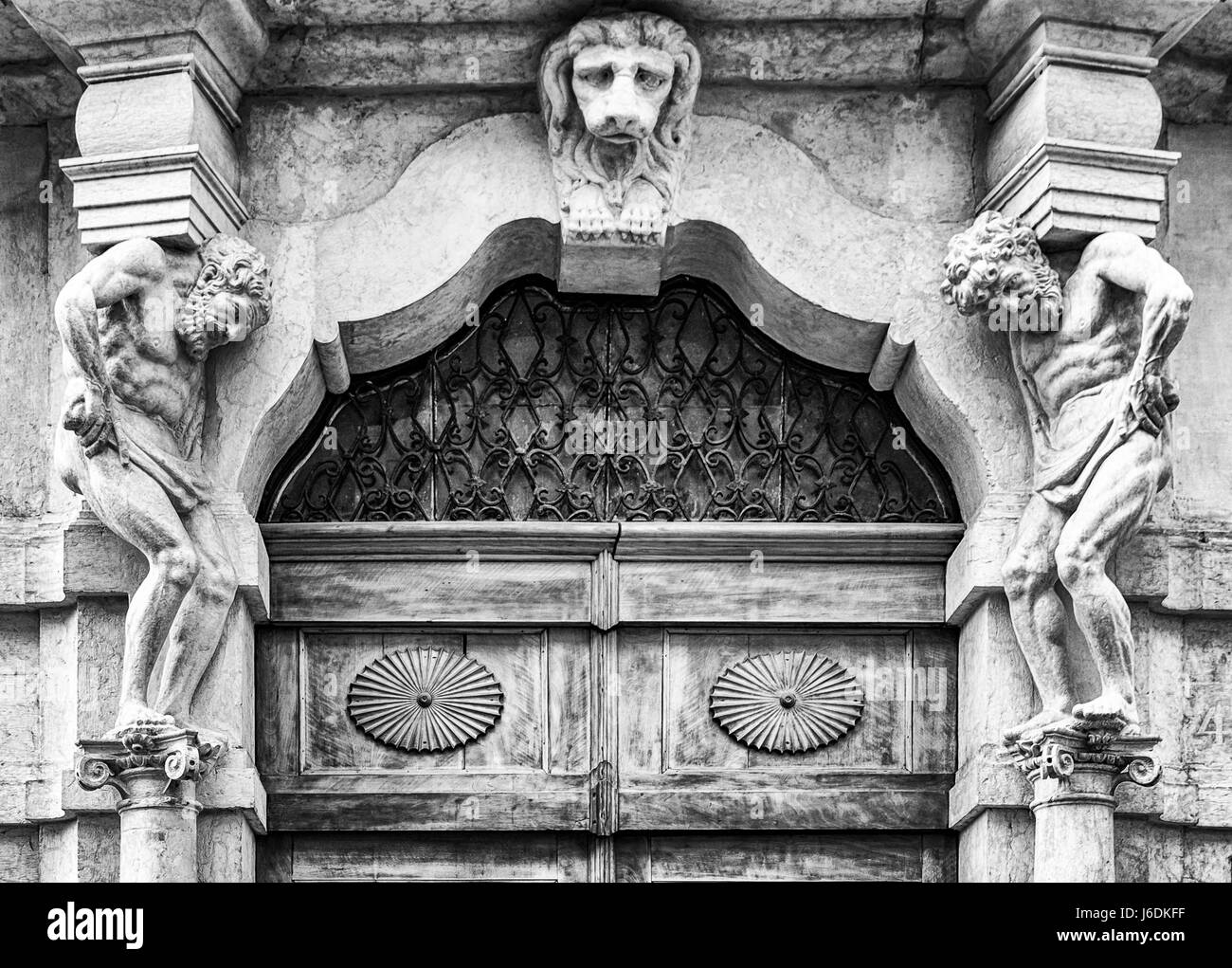 Vecchia pietra bianca ingresso e portale in legno con le statue che supportano le colonne laterali. Foto Stock