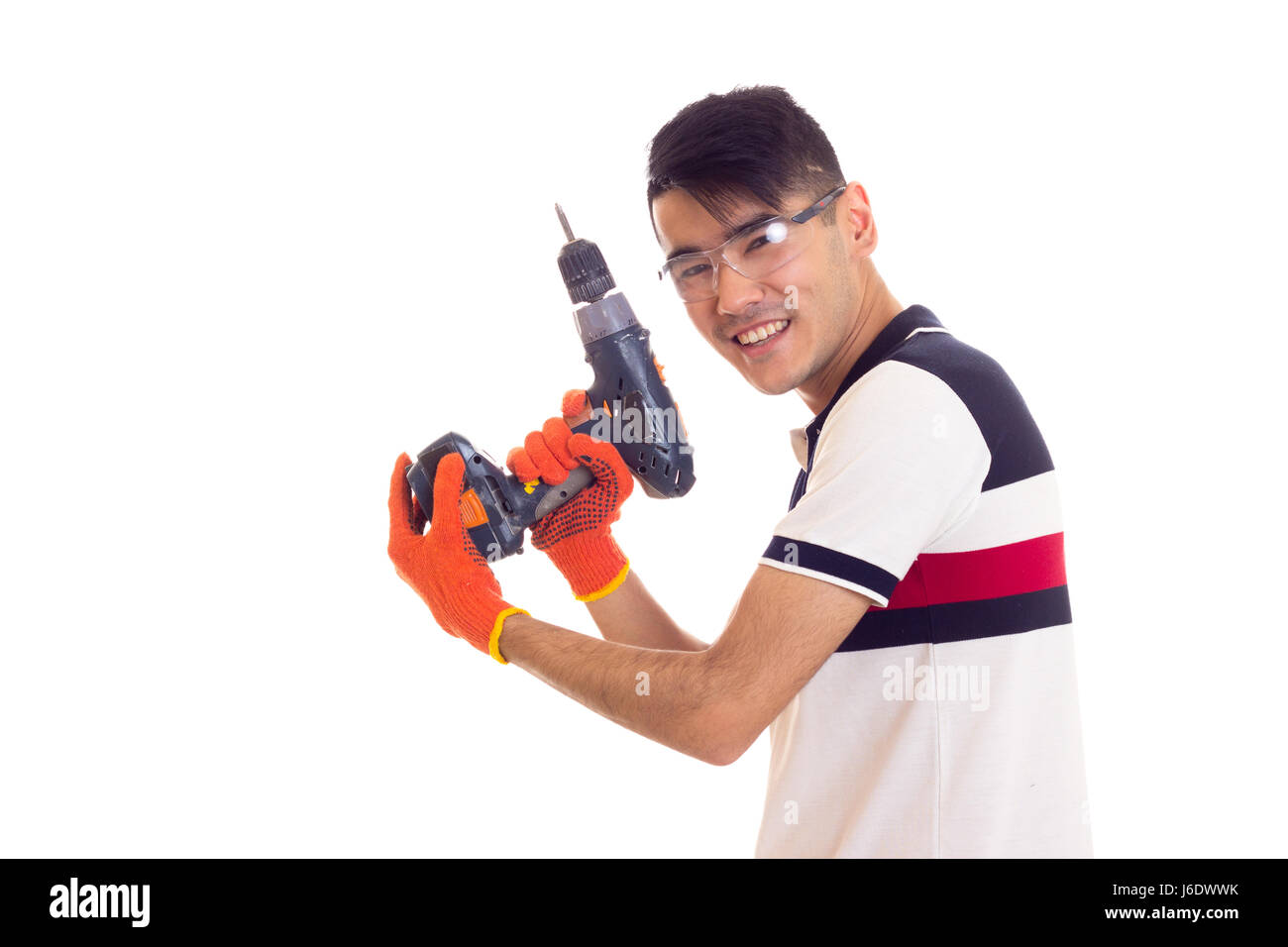 Giovane con guanti e occhiali di protezione tenendo cacciavite elettrico Foto Stock