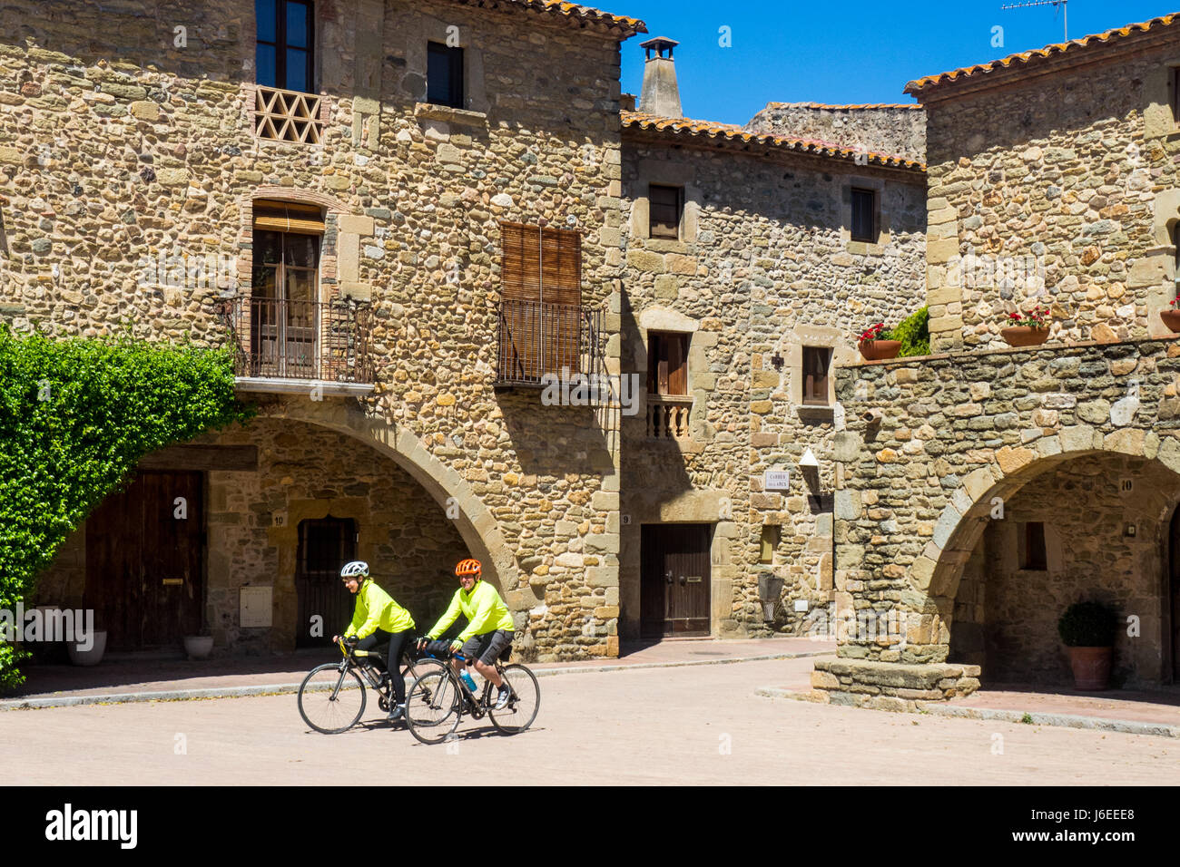 Due cicloturisti cavalcare le loro biciclette titanio in Plaça Jaume I, a Monells, provincia di Girona, Spagna. Foto Stock