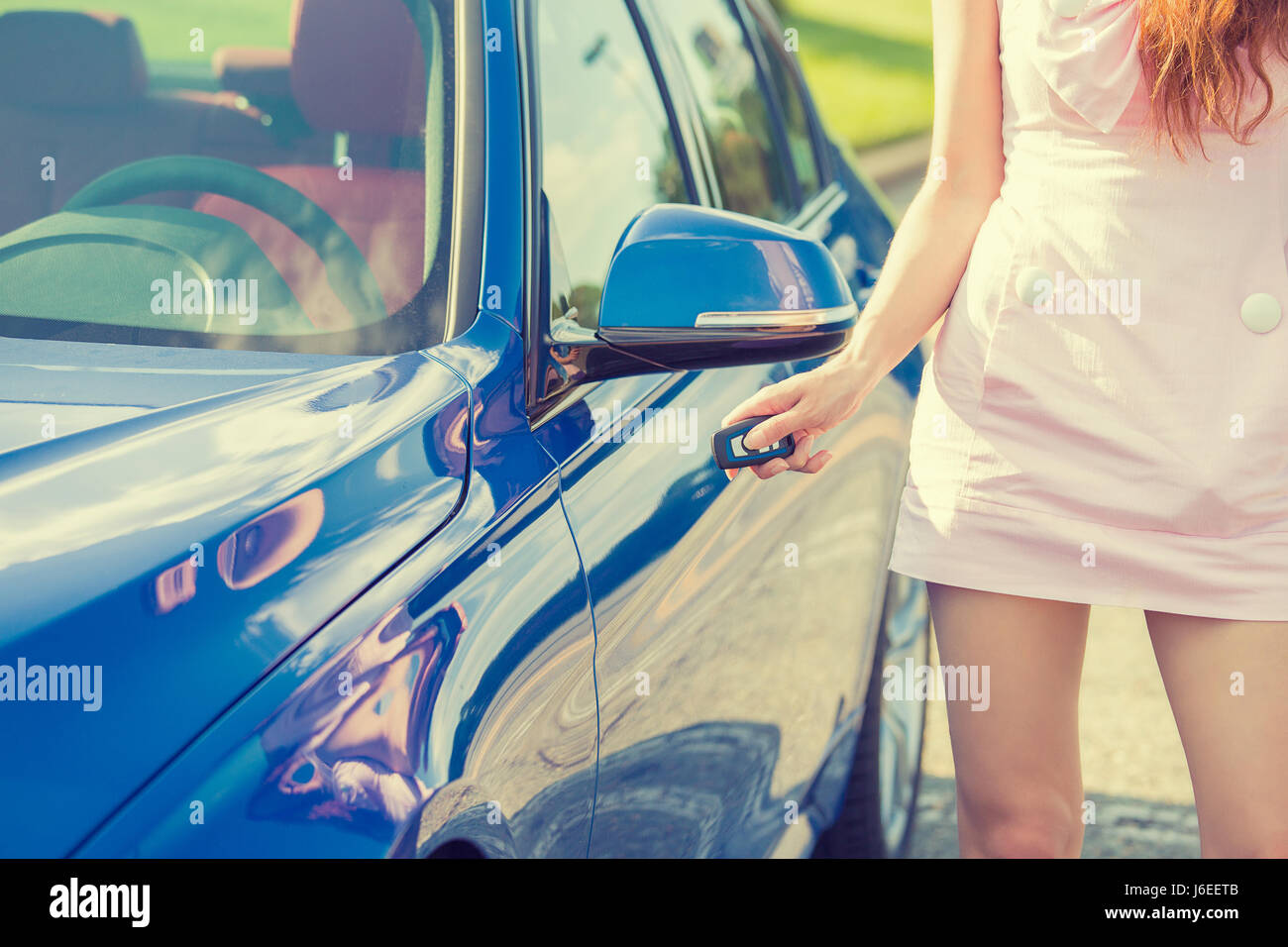 Giovane donna preme il pulsante di sblocco sul car telecomando si sblocca porta sistemi di allarme. La comodità del veicolo per la sicurezza del sistema di sicurezza Foto Stock