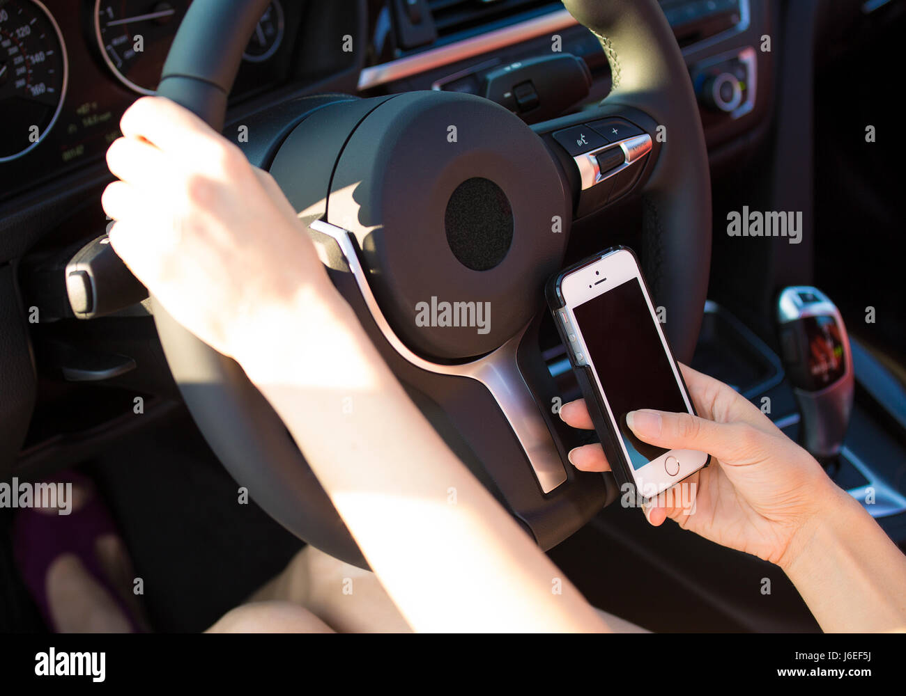 Closeup imprenditrice, donna mani, inviare un messaggio di testo sul telefono intelligente mentre si guida per lavoro. La sicurezza del traffico, norme, regolamenti concetto. Driver difettoso Foto Stock