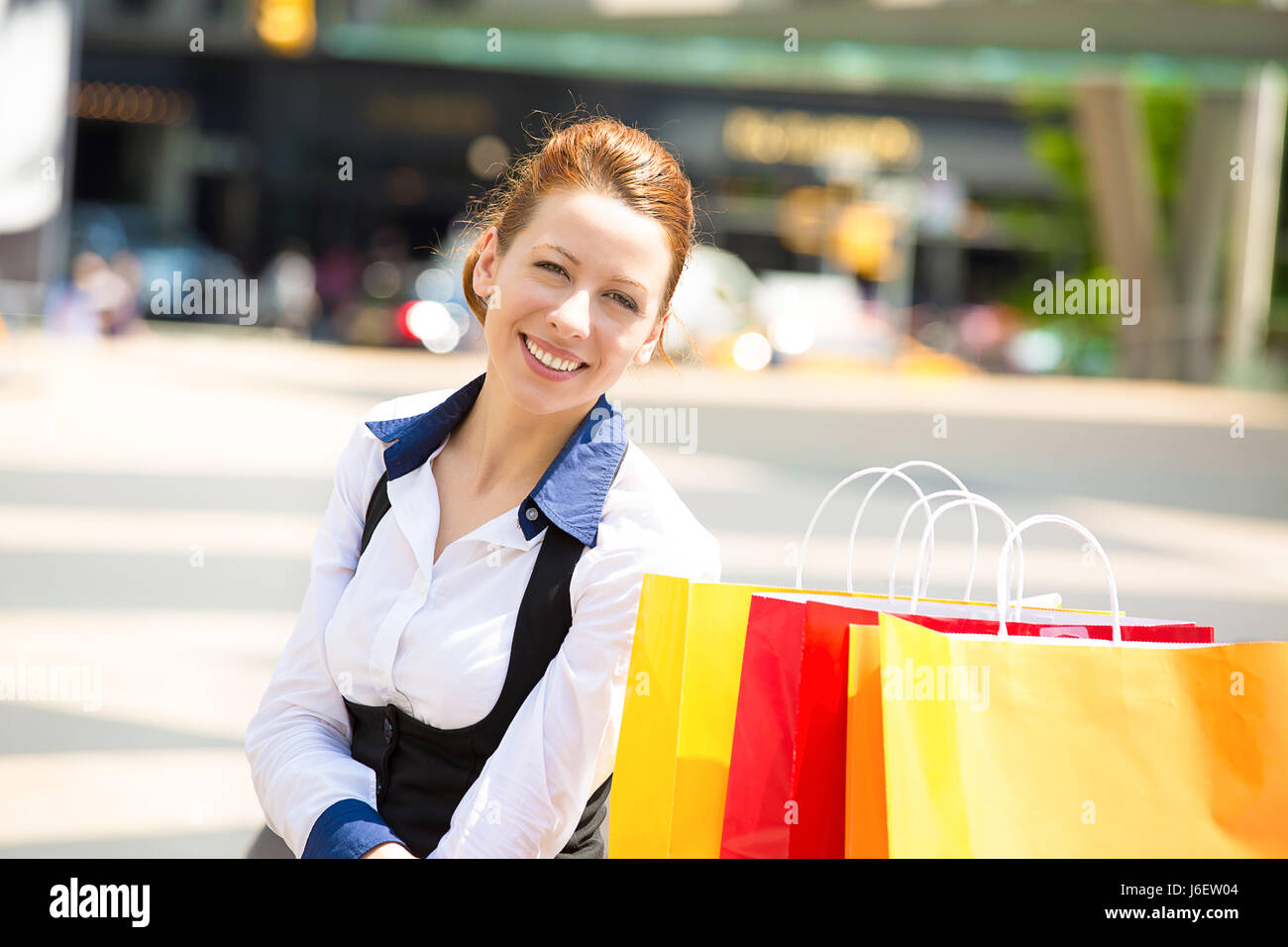 Donna Shopping in New York City. Bella felice, sorridente estate shopper con giallo shopping bags rilassante sulla giornata di sole al di fuori. Emozioni positive, f Foto Stock