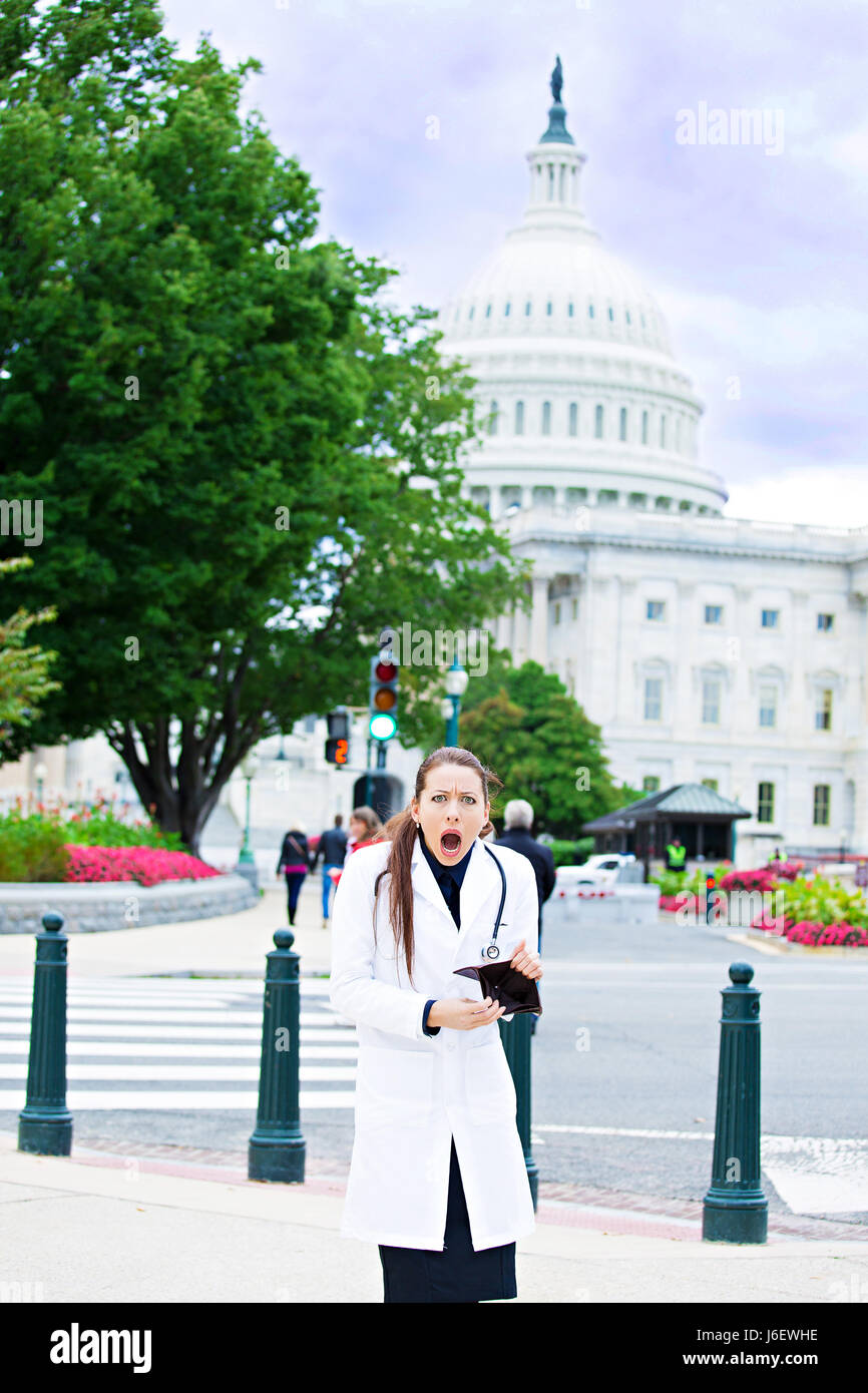 Ritratto femminile professionista sanitario a Washington dc, ha rotto la donna medico azienda portafoglio vuoto isolato dal Capitol Building sfondo. Healthcare re Foto Stock