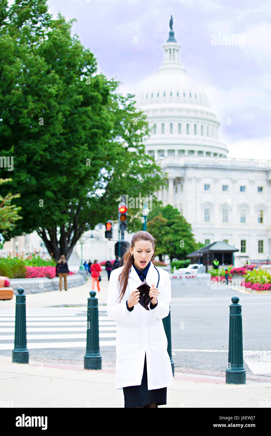 Ritratto femminile professionista sanitario a Washington dc, ha rotto la donna medico azienda portafoglio vuoto isolato dal Capitol Building sfondo. Healthcare re Foto Stock