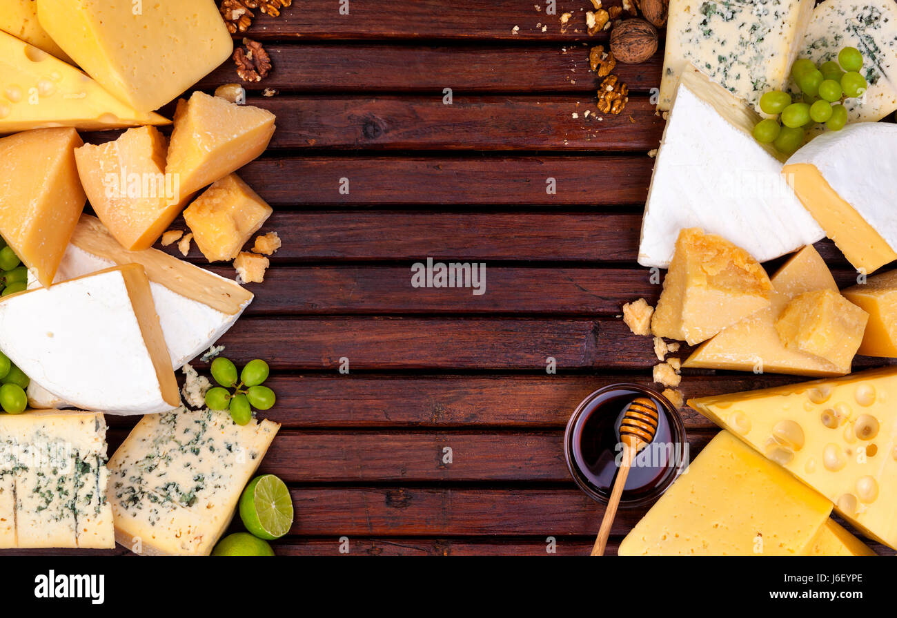 Vari tipi di formaggio su un tavolo di legno dello sfondo. Il Cheddar, parmigiano, emmental, formaggi blu. Vista superiore, copia dello spazio. Foto Stock