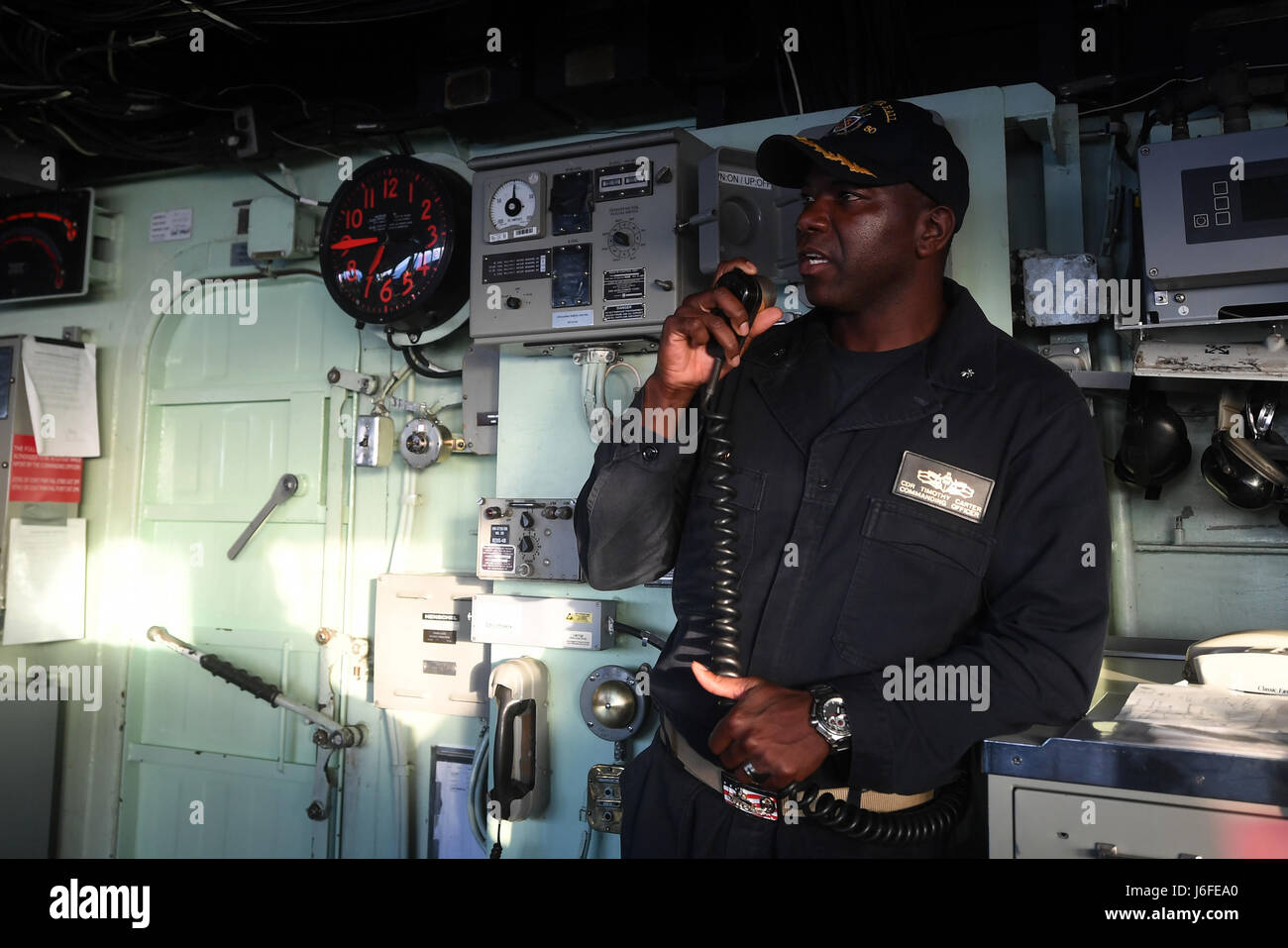 170512-N-ME988-551 U.S. 5TH FLOTTA AREA DI OPERAZIONI (12 maggio 2017) della Cmdr. Timothy Carter, comandante a bordo del dock anfibio sbarco nave USS Carter Hall (LSD 50), utilizza la nave 1MC sistema di annuncio a consegnare un messaggio per l'equipaggio. Carter Hall, parte di Bataan anfibio gruppo pronto, è distribuito negli Stati Uniti Quinta Flotta area di operazioni a sostegno della sicurezza marittima operazioni destinate a rassicurare gli alleati e partner e preservare la libertà di navigazione e il libero flusso di commercio nella regione. (U.S. Foto di Marina di Massa lo specialista di comunicazione 1a classe Darren M. MOO Foto Stock