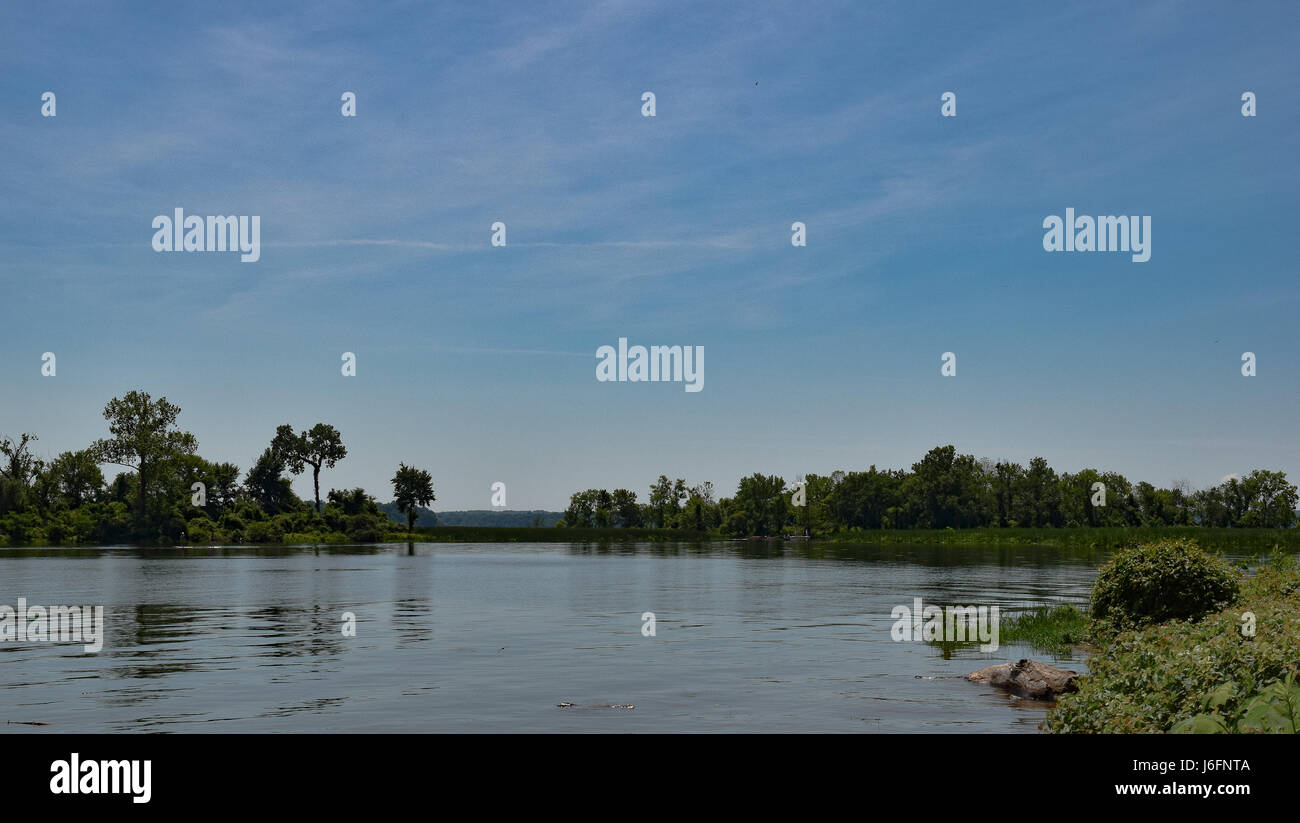 Un corpo di pacifica di acqua sotto un cielo blu con nuvole wispy Foto Stock