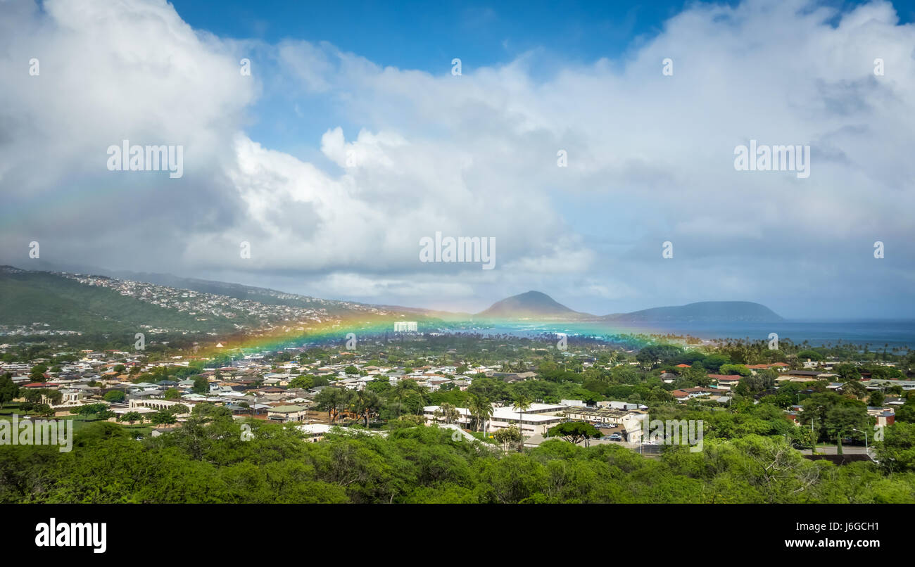Un luminoso e vibrante ultra-bassa Hawaiian rainbow sulla lussureggiante vegetazione verde di un quartiere residenziale di Honolulu. Foto Stock