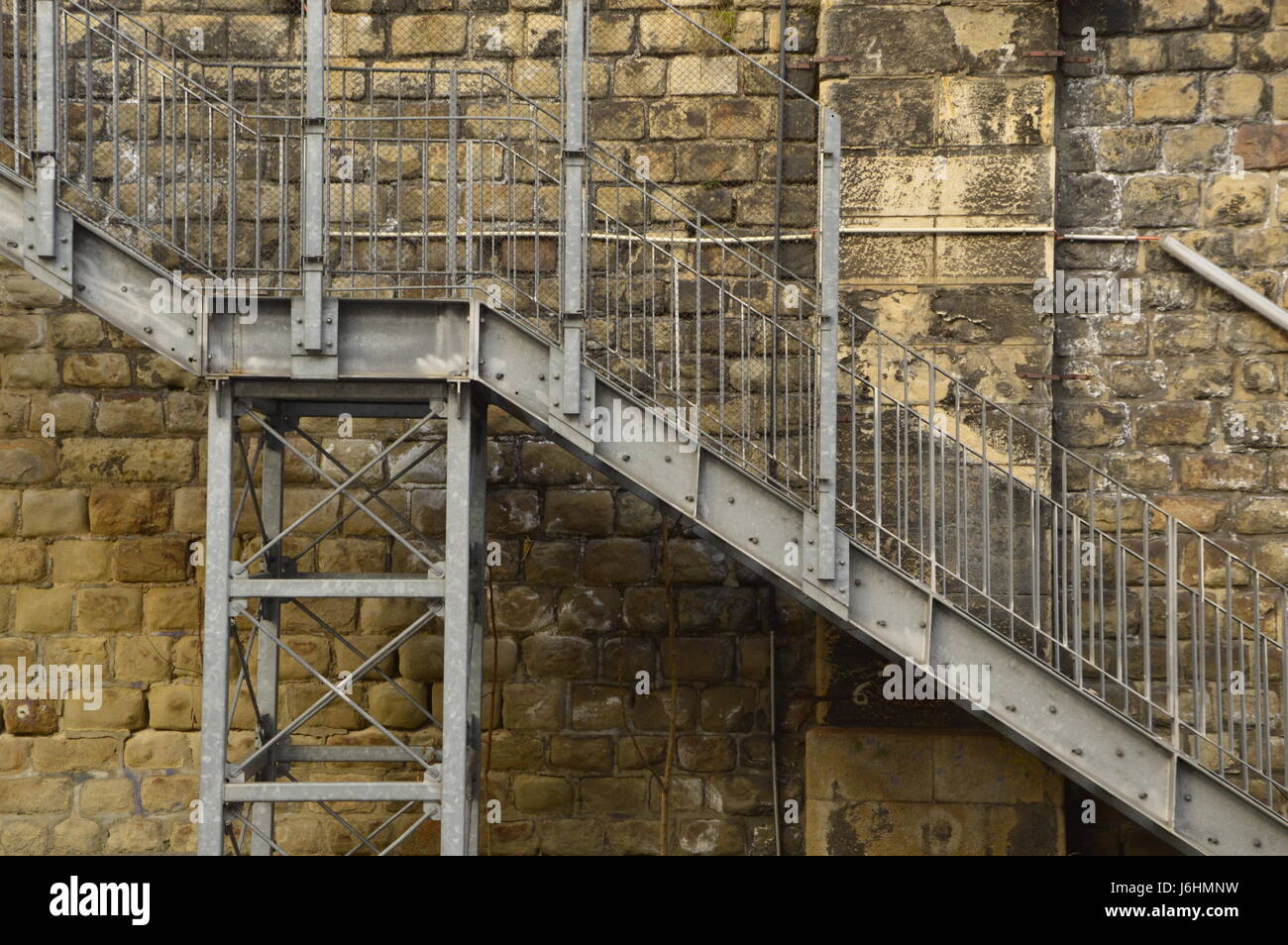 Industriali in metallo scale presso il muro di pietra. Foto Stock