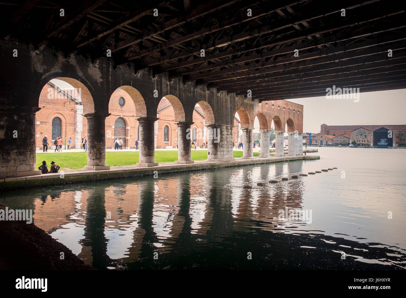 Venezia, Castello, Porto Arsenale. Vista di vecchi edifici coperti dal dock di Gaggiandre con persone che visitano la Biennale di Venezia in background Foto Stock