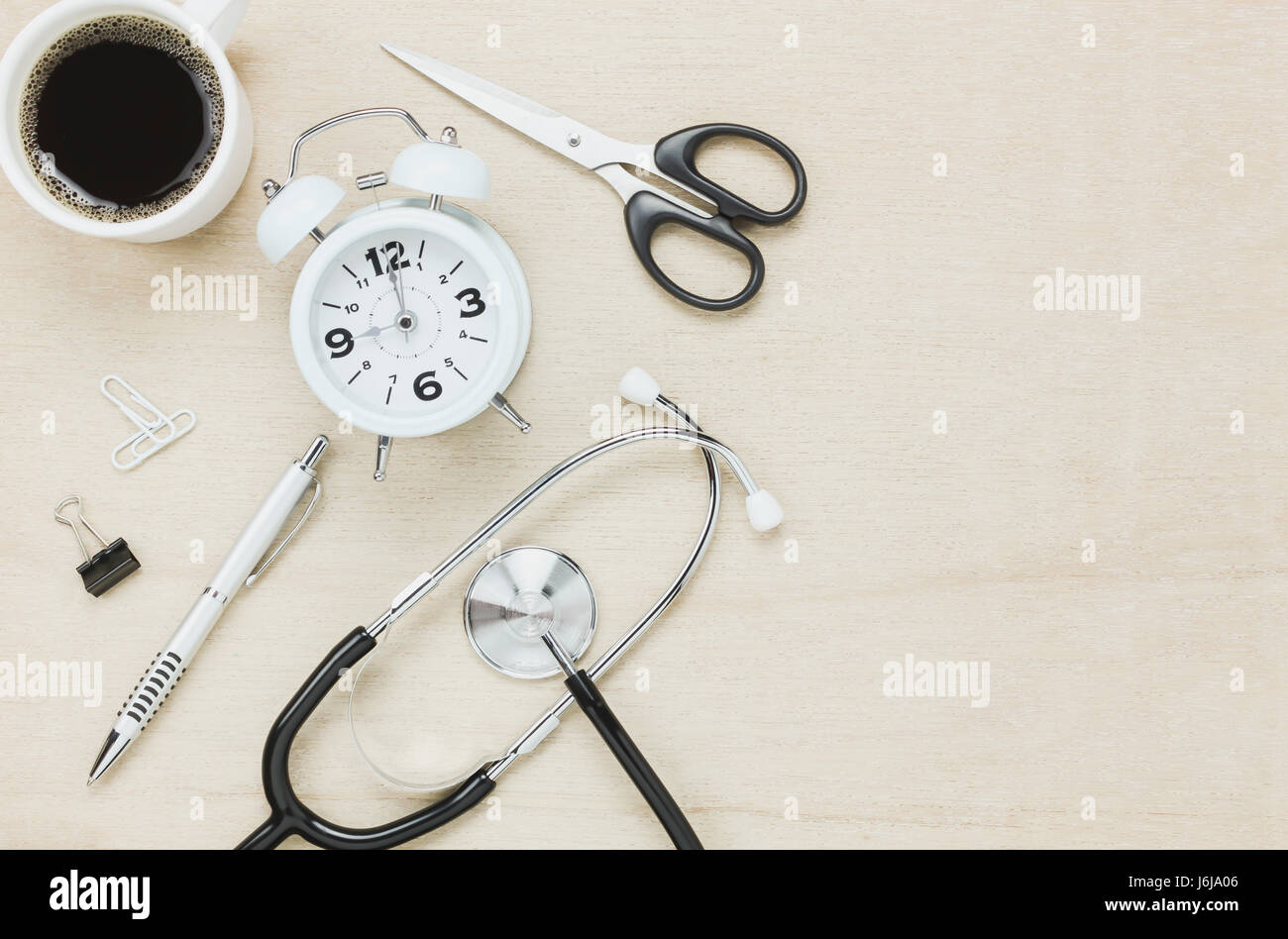 Vista dall'alto uno stetoscopio con orologio forbici caffè con penna su sfondo di legno. Foto Stock