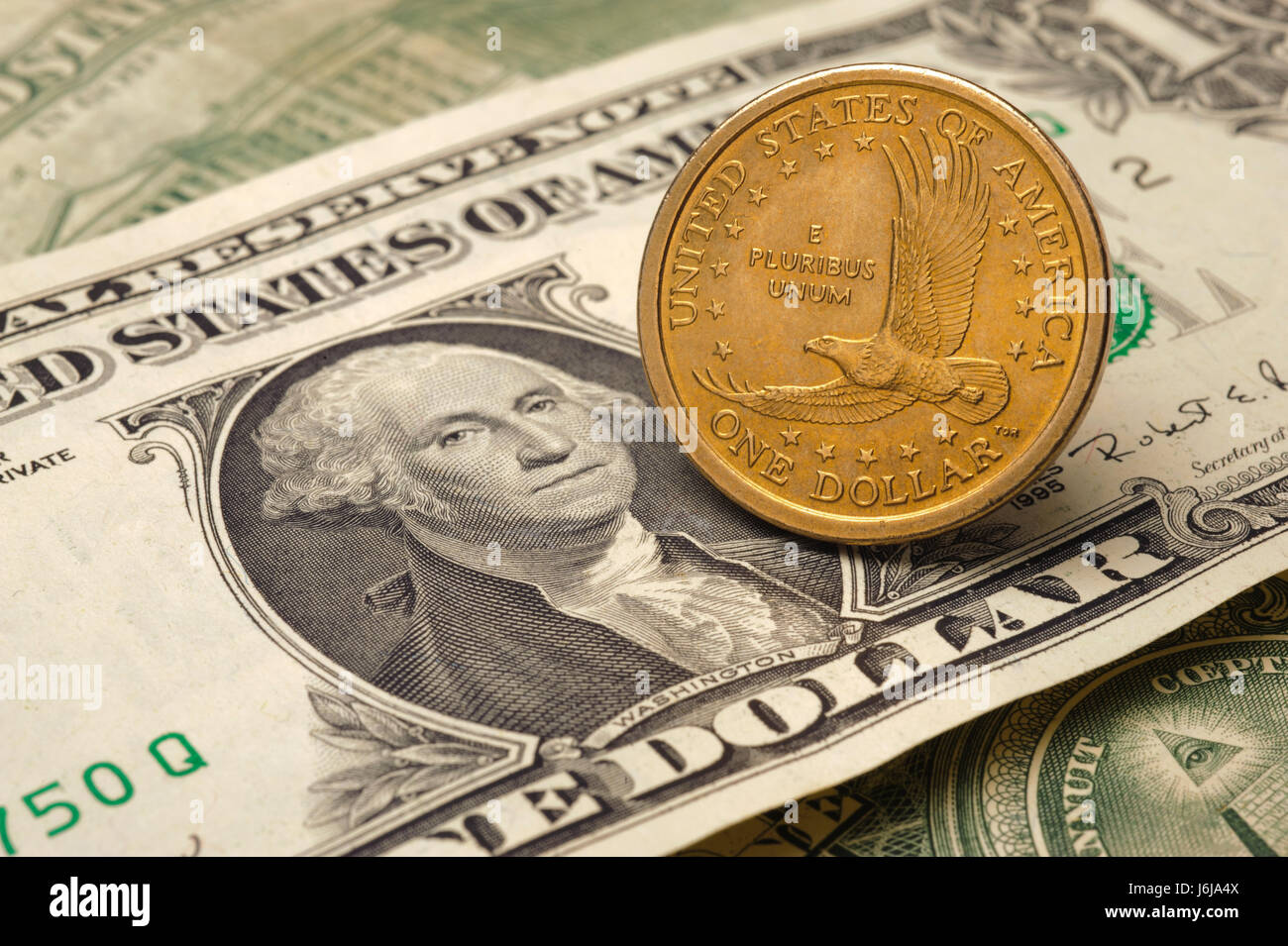 Un dollaro moneta della valuta statunitense posa su una banconota del dollaro Foto Stock