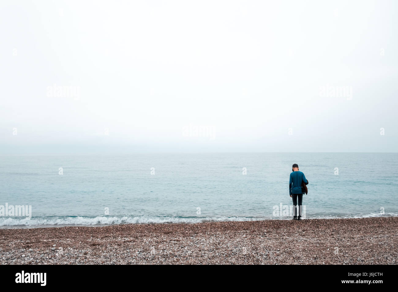 Da soli boy alloggiare vicino al mare. Cielo nuvoloso e nebbioso acqua Foto Stock