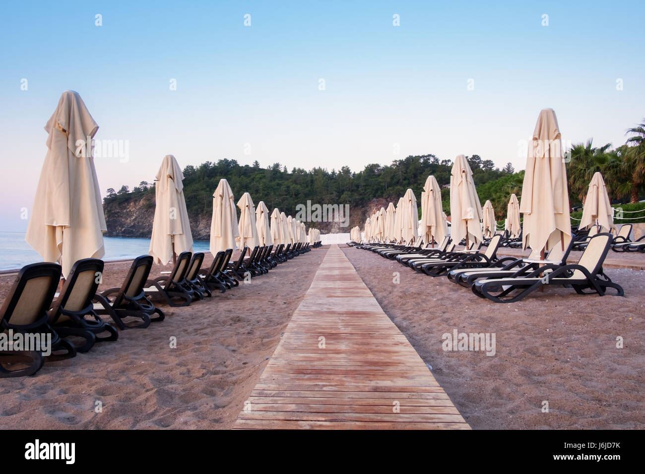 Fila di ombrelloni sulla spiaggia del mare. Vista tranquilla del mare Mediterraneo. Incredibile rosa alba con cielo chiaro. Location posizione: Turchia Kemer. Foto Stock