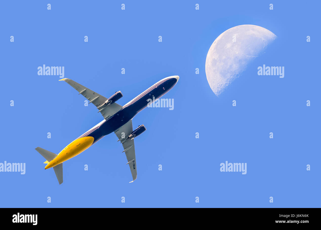 Fly me la luna. Passeggero aereo jet vola alto contro il cielo blu con la luna in distanza. Il viaggio in aereo. Volare sopra le nuvole. Foto Stock