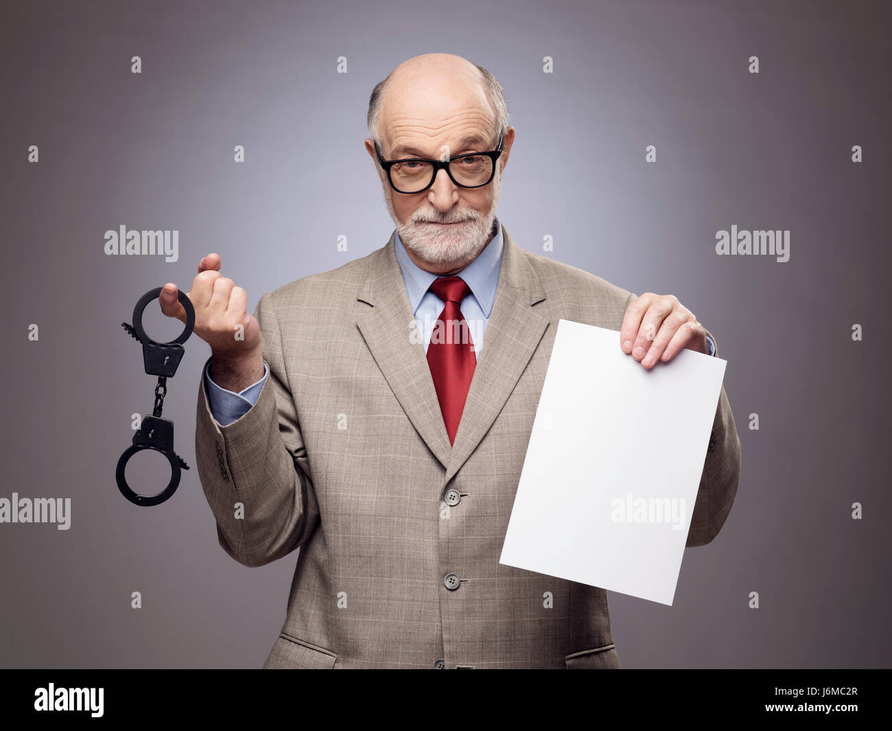 Senior business man con le manette e vuoto di carta contratto accenni al pericolo di reati finanziari Foto Stock