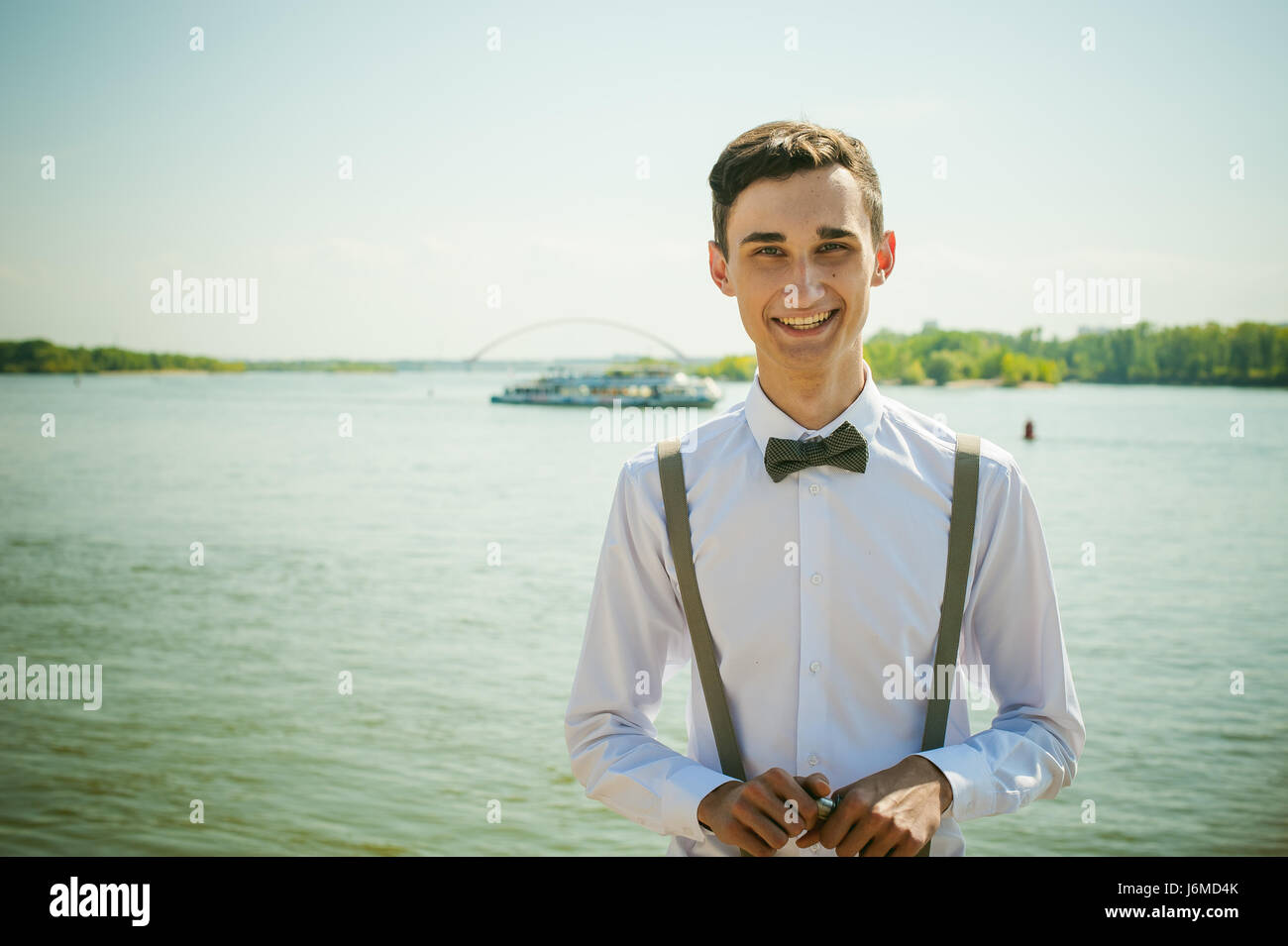 Giovane uomo magro, elegantemente vestito elegantemente in una camicia  bianca, grigio pantaloni con bretelle e il filtro bow tie. Ritratto di un  ragazzo sullo sfondo di un rive Foto stock - Alamy