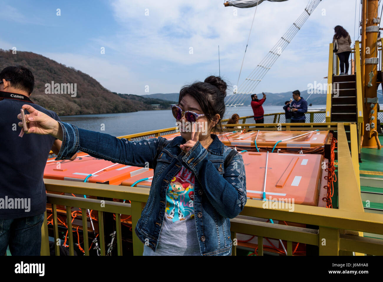 Giovane ragazza asiatica prendendo un selfie su una replica di una nave pirata. Foto Stock