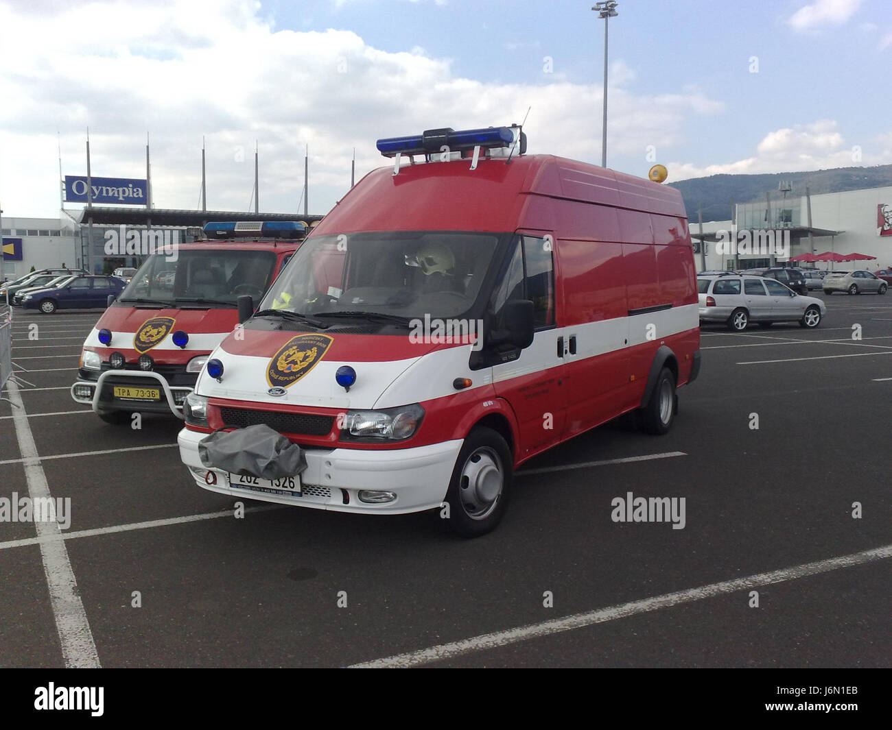 Questa immagine raffigura probabilmente i vigili del fuoco (Hasici) vicino alla sede olimpica (Olympie), probabilmente durante un evento pubblico o una risposta di emergenza, che mostrano il ruolo dei servizi di emergenza nella Repubblica Ceca o in una regione correlata. Foto Stock