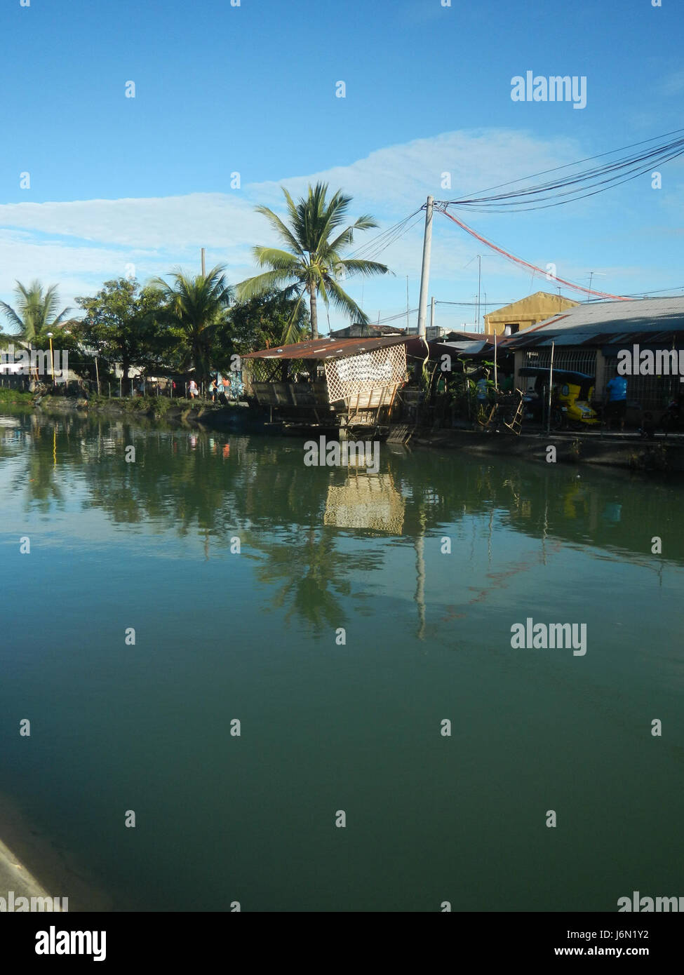 Questa immagine mostra le risaie e i sistemi di irrigazione a Bagong Nayon, Baliuag, Bulacan. I campi sono essenziali per l'agricoltura locale, con ponti stradali che facilitano il trasporto nelle zone rurali della regione. Foto Stock