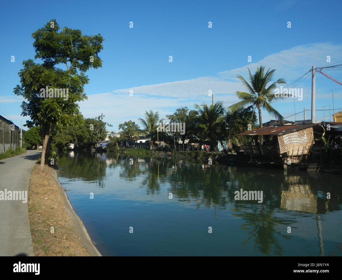 Questa immagine mostra il sistema di irrigazione nelle risaie di Bagong Nayon a Baliuag, Bulacan. Le pratiche agricole della regione sono sostenute da ponti stradali che facilitano l'accesso e la gestione delle risorse idriche per l'agricoltura. Foto Stock