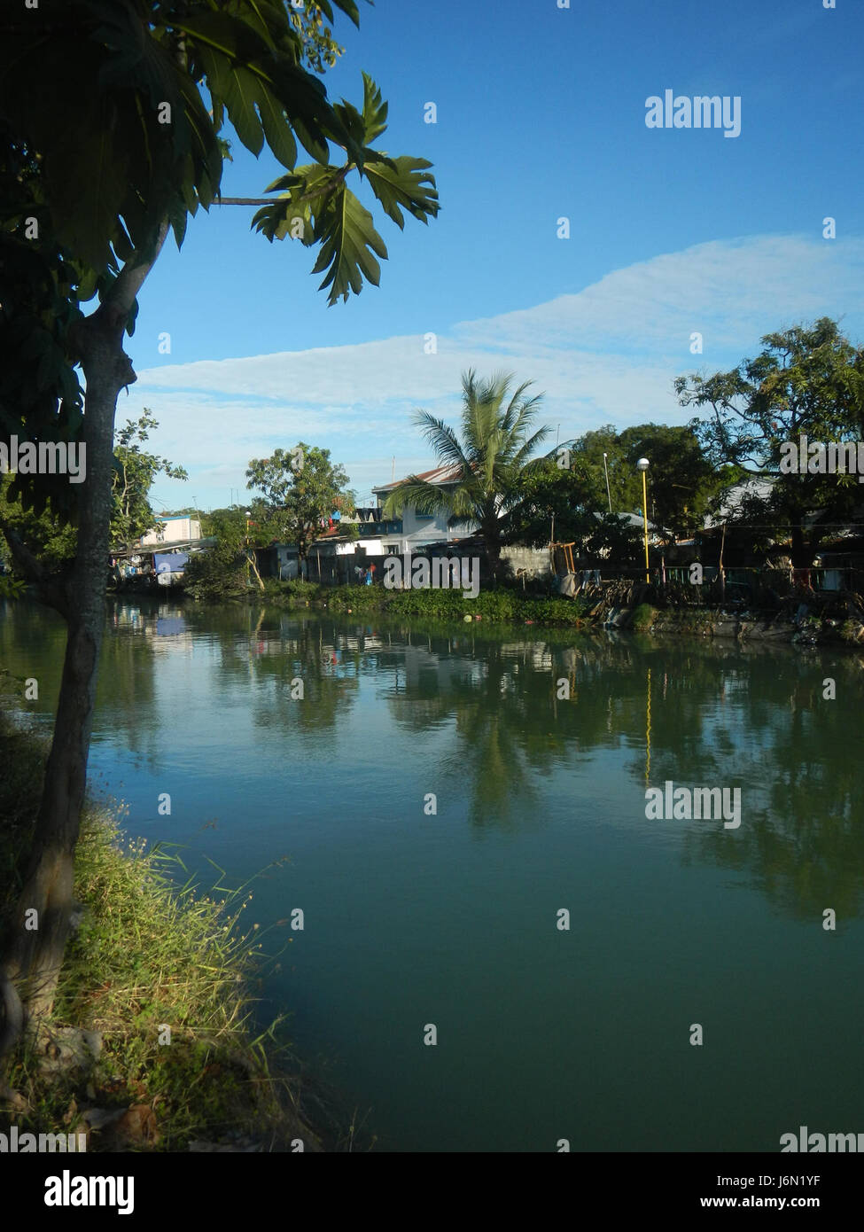 Le risaie di Bagong Nayon, Baliuag, Bulacan, fanno parte di un vasto sistema di irrigazione progettato per sostenere le attività agricole nella regione. I ponti stradali della zona svolgono un ruolo fondamentale nel facilitare il trasporto e l'accesso a queste zone agricole. Foto Stock