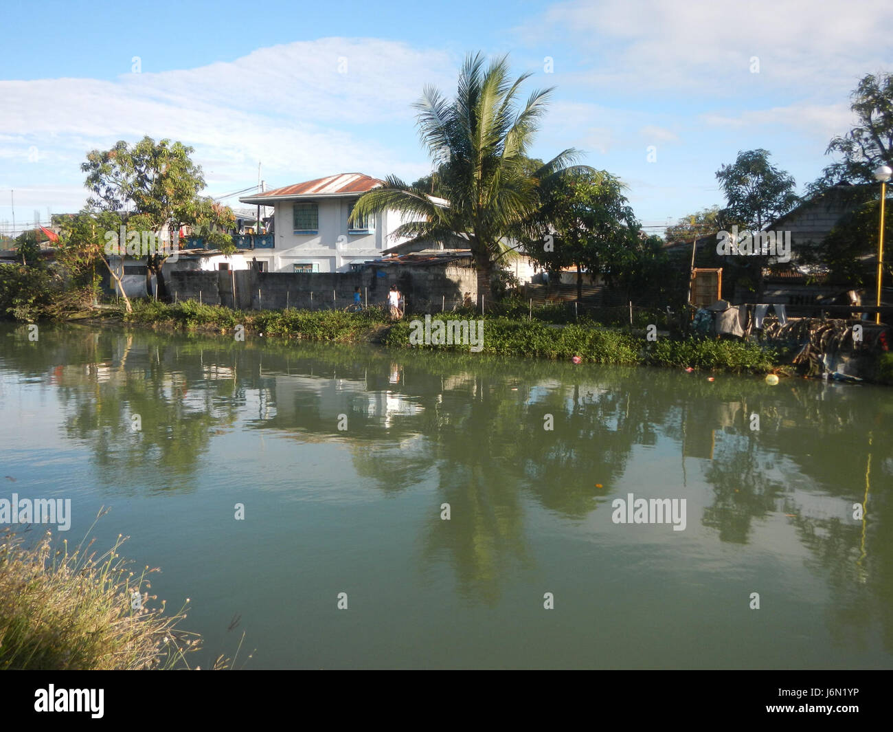 Questa immagine mostra il sistema di irrigazione utilizzato nelle risaie di Bagong Nayon, Baliuag, Bulacan, insieme ai ponti stradali. Essa mette in evidenza le infrastrutture agricole essenziali per la coltivazione del riso nella zona, dimostrando l'interconnessione tra strade e sistemi di irrigazione. Foto Stock