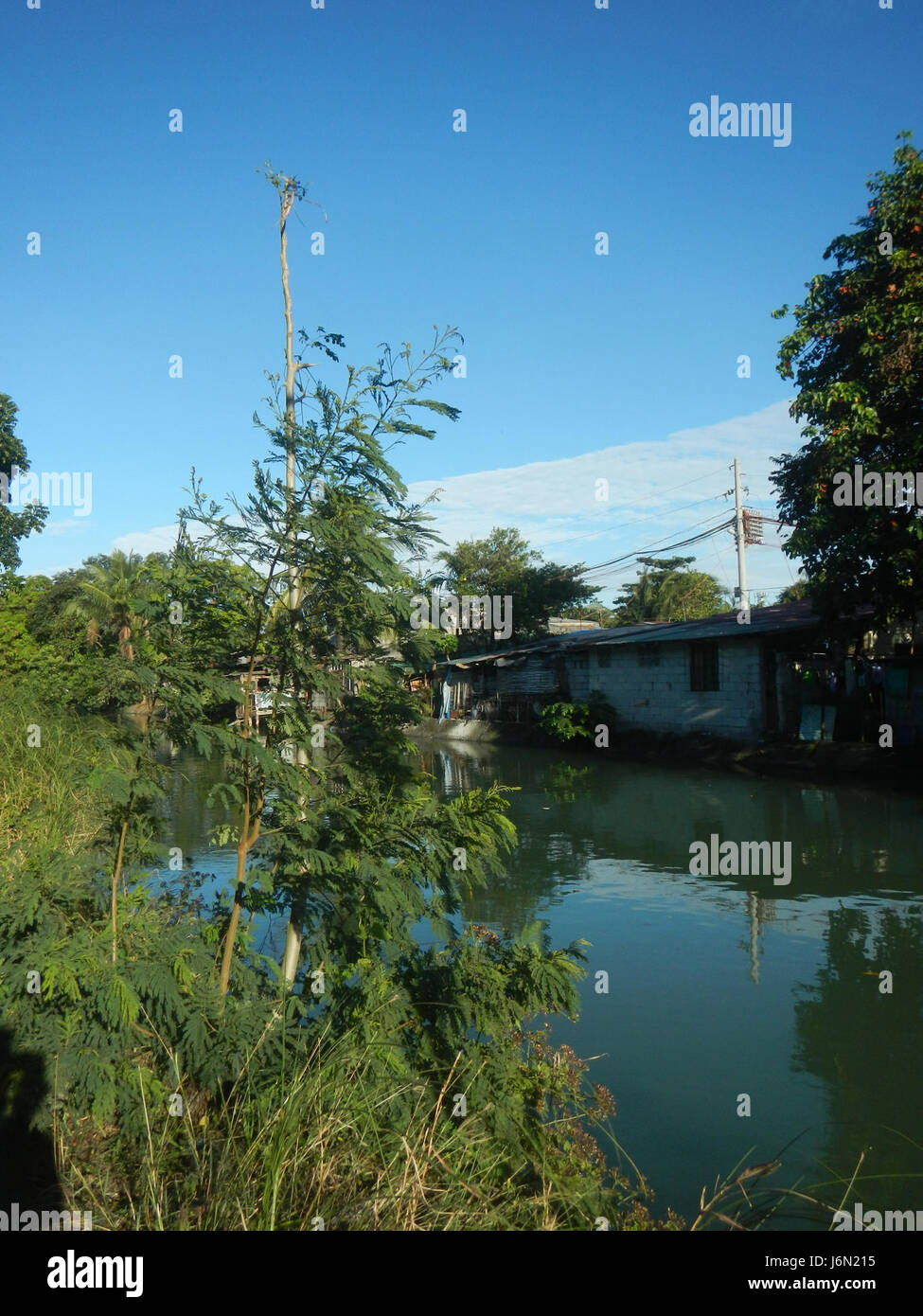 Questa immagine cattura il sistema di irrigazione nelle risaie di Bagong Nayon, Baliuag, Bulacan. Essa mette in evidenza i ponti stradali che sostengono le infrastrutture agricole che facilitano la distribuzione idrica, essenziale per la coltivazione del riso in questa regione rurale delle Filippine. Foto Stock