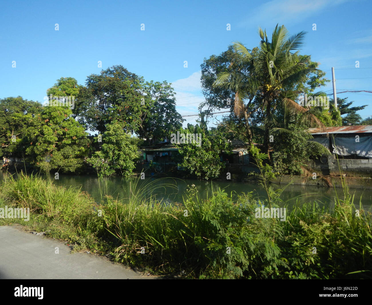 Questa fotografia cattura il sistema di irrigazione nelle risaie di Bagong Nayon, Baliuag, Bulacan. L'immagine mette in evidenza i ponti stradali e il paesaggio agricolo, sottolineando la gestione dell'acqua nella coltivazione del riso. Foto Stock