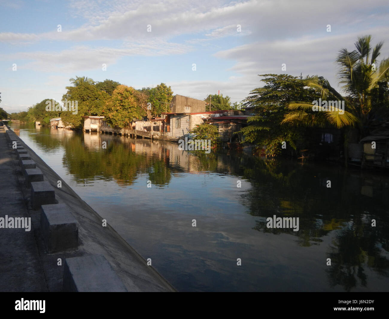 Questa immagine descrive il paesaggio rurale di Sabang, Baliuag, Bulacan, caratterizzato da ampie risaie, praterie, case e un sistema di irrigazione, nonché ponti stradali locali critici per il trasporto e l'agricoltura. Foto Stock