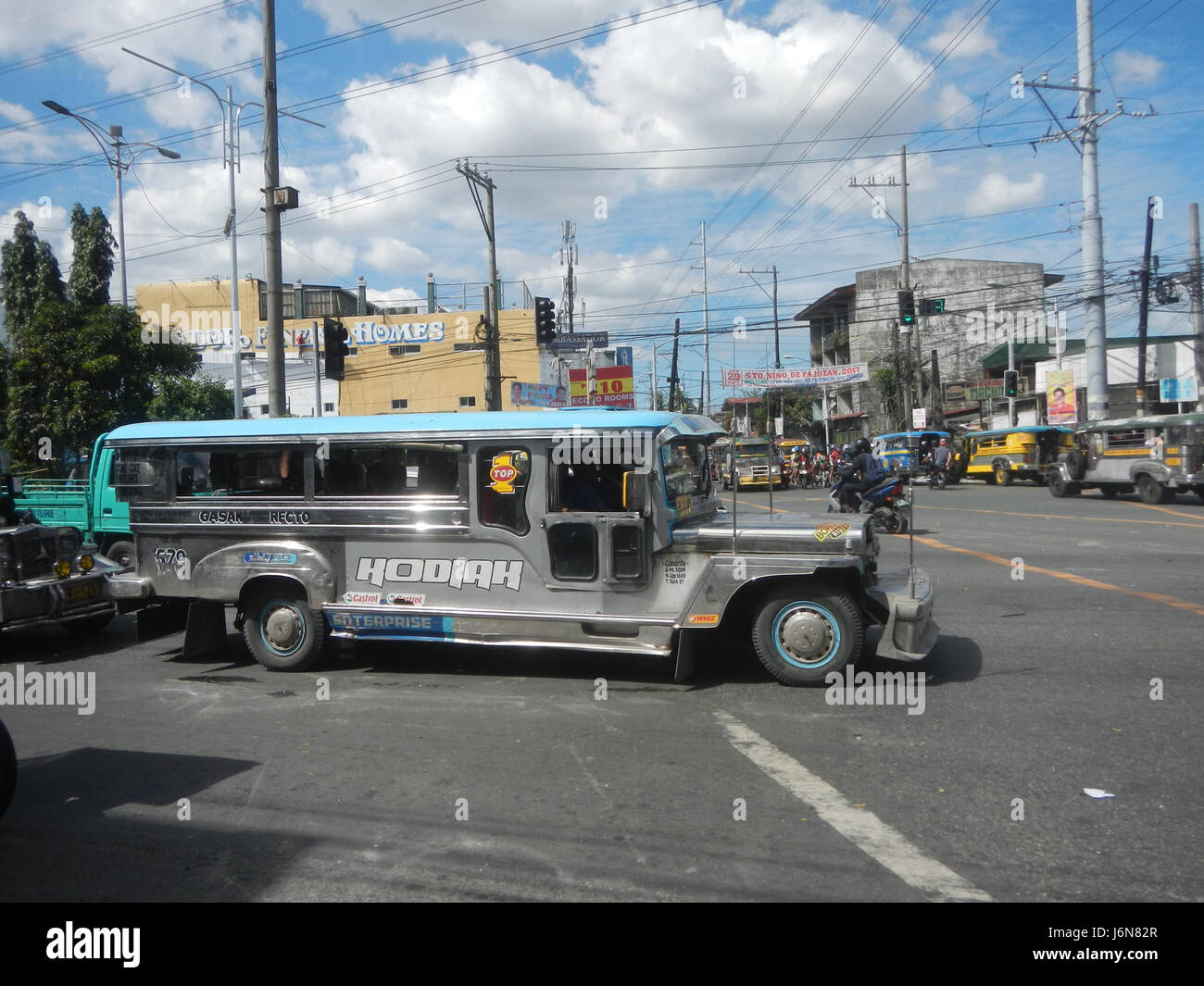 Questa immagine mostra una vivace scena urbana lungo A. Mabini Street e C-13 Road nella città di Caloocan, con edifici commerciali e infrastrutture locali. Rappresenta lo sviluppo urbano e la crescita della città, sottolineando l'importanza dei trasporti e delle aree commerciali nella regione. Foto Stock
