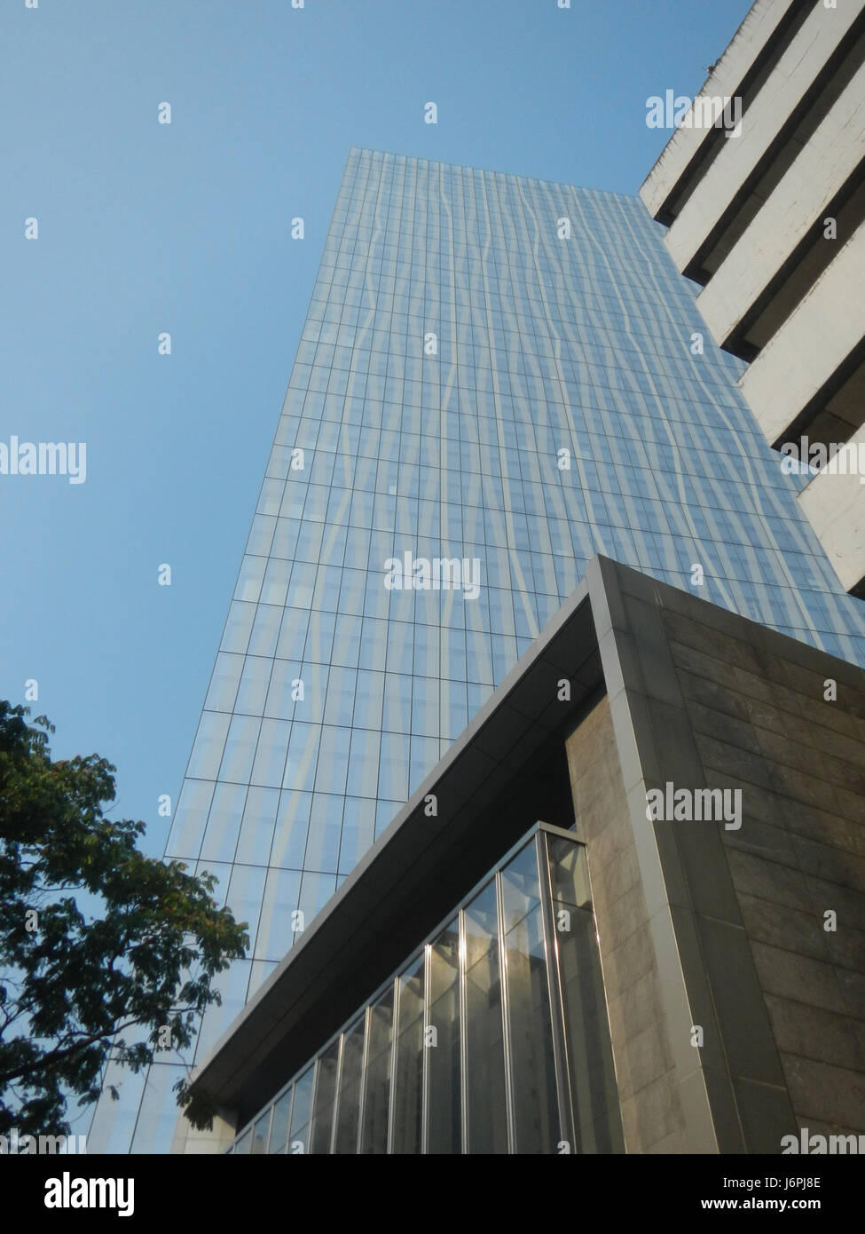 L'immagine mostra l'edificio Urdaneta Zuellig, situato sul Paseo de Roxas a Makati, un importante quartiere finanziario della Metro Manila. Questo moderno grattacielo è uno degli edifici simbolo della città, noto per il suo design contemporaneo e il suo significato commerciale. Foto Stock